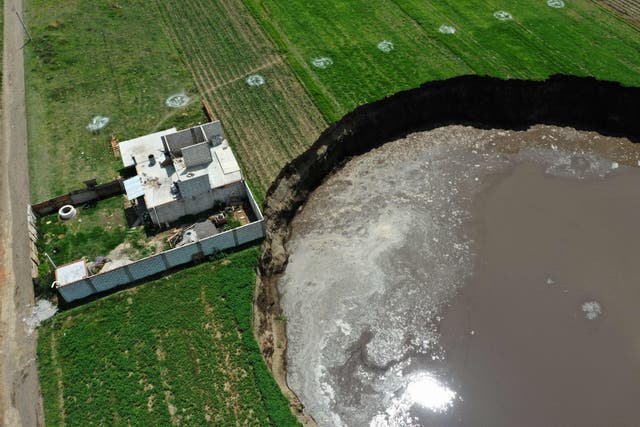 <p>Aerial view of a sinkhole nearing a house in a farmland in Santa Maria Zacatepec, state of Puebla, Mexico</p>