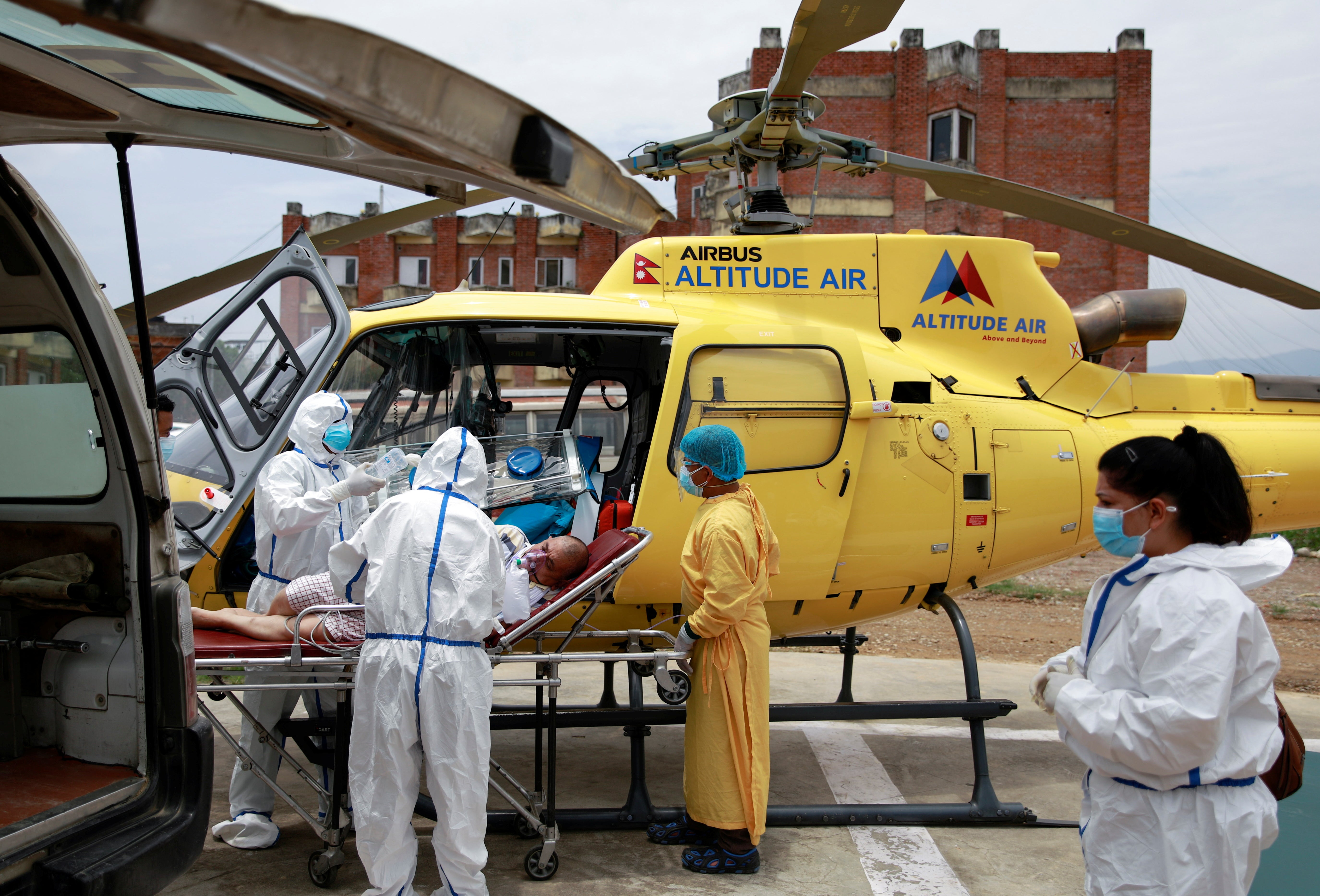 Health workers in Kathmandu carry a Covid patient from a helicopter to an ambulance after being airlifted due to health complications