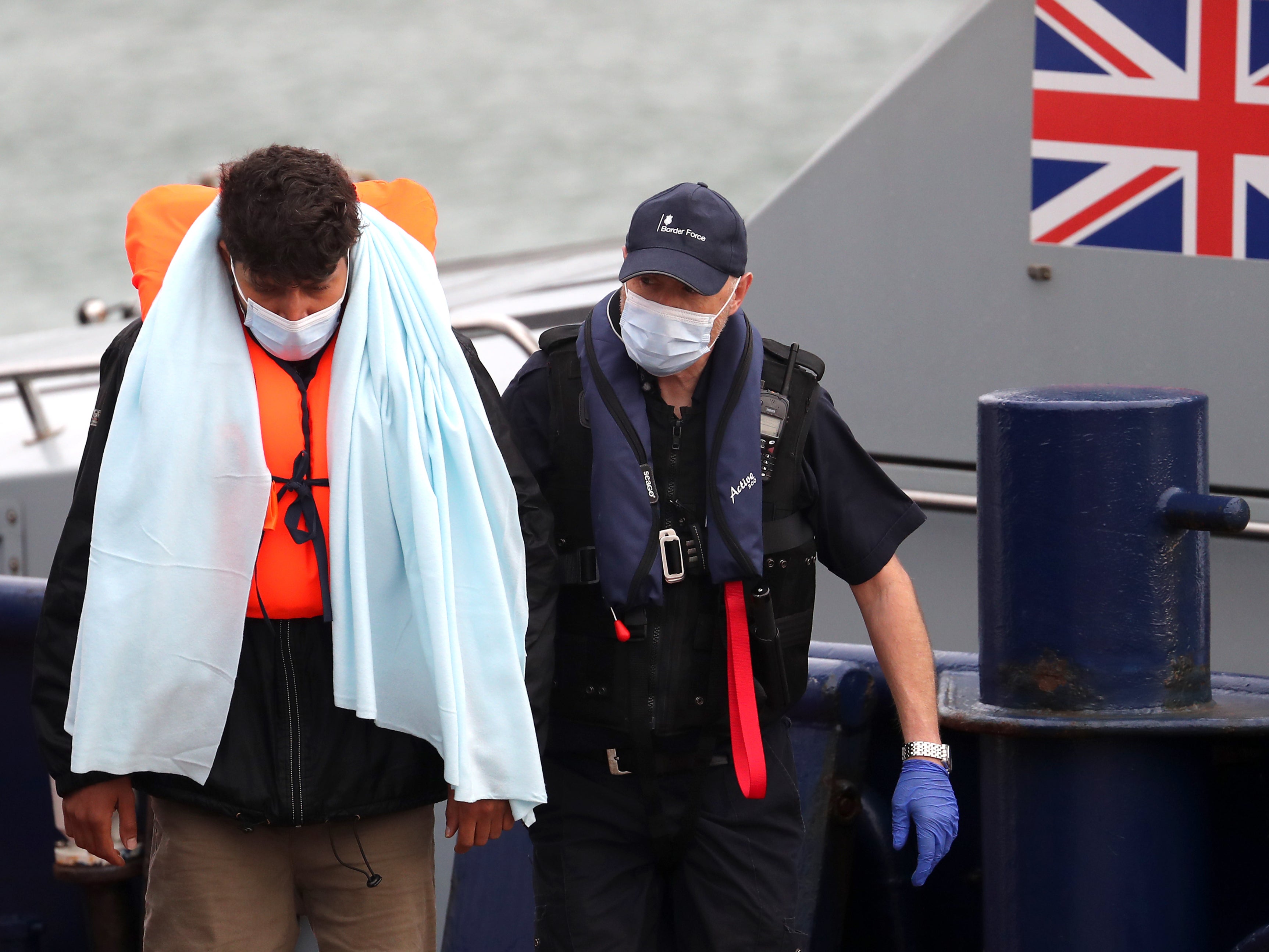 <p>A man is brought in to Dover by Border Force officials on 3 June</p>