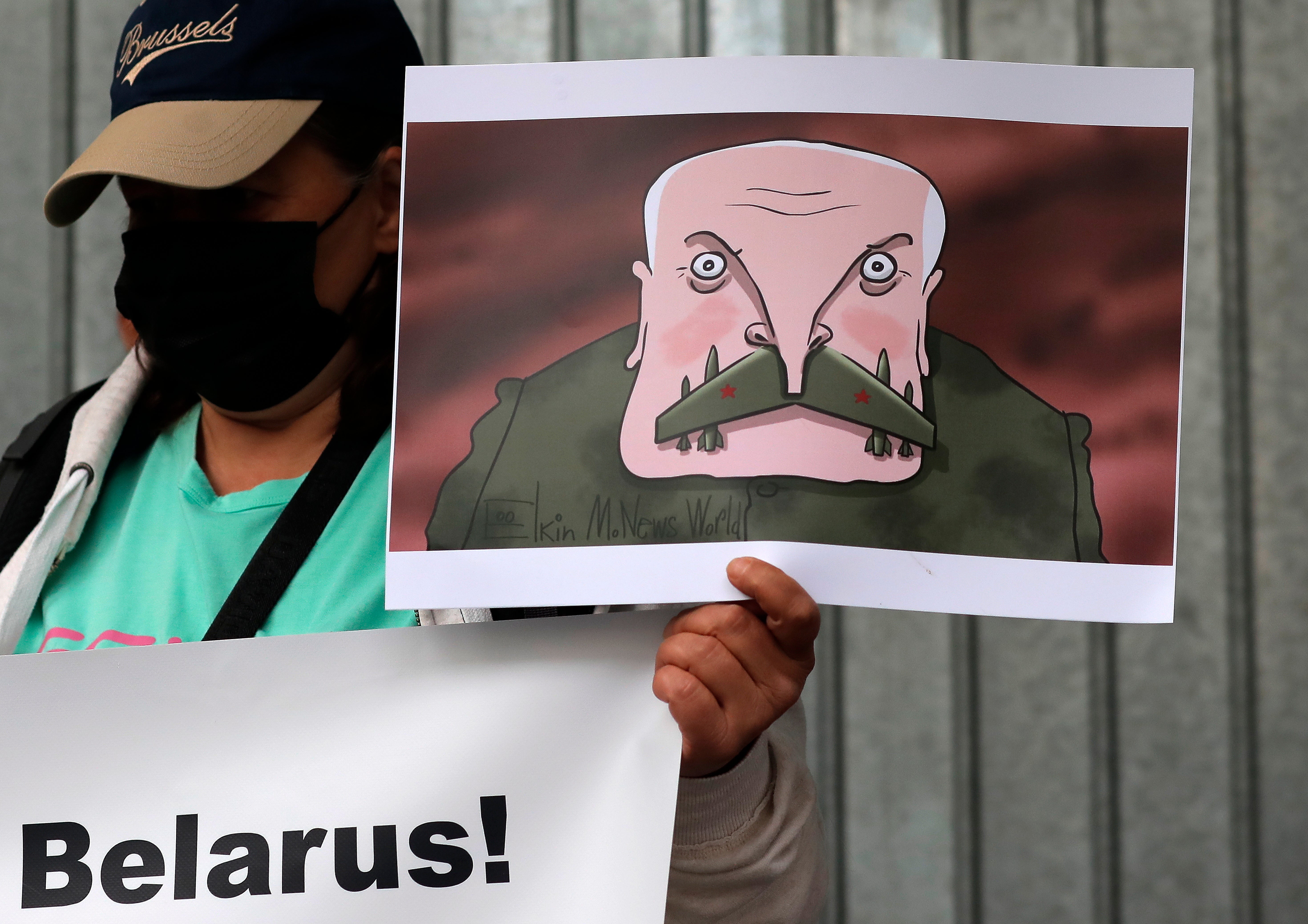 A civil rights activist holds a placard depicting a cartoon of the Belarusian president