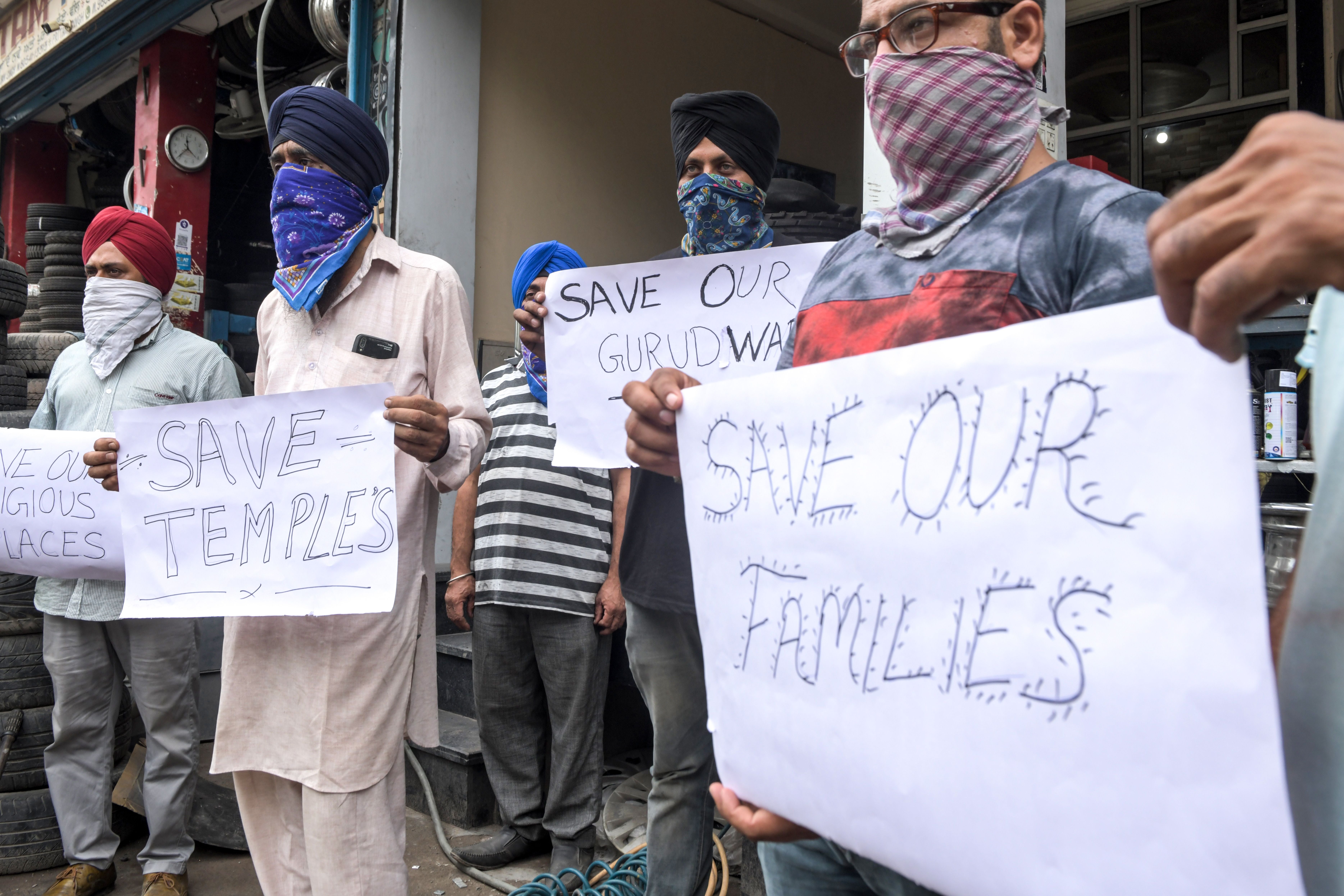 Afghan Sikh refugees hold placards as they demand that the Pakistani and Afghani governments protect their families and religious places