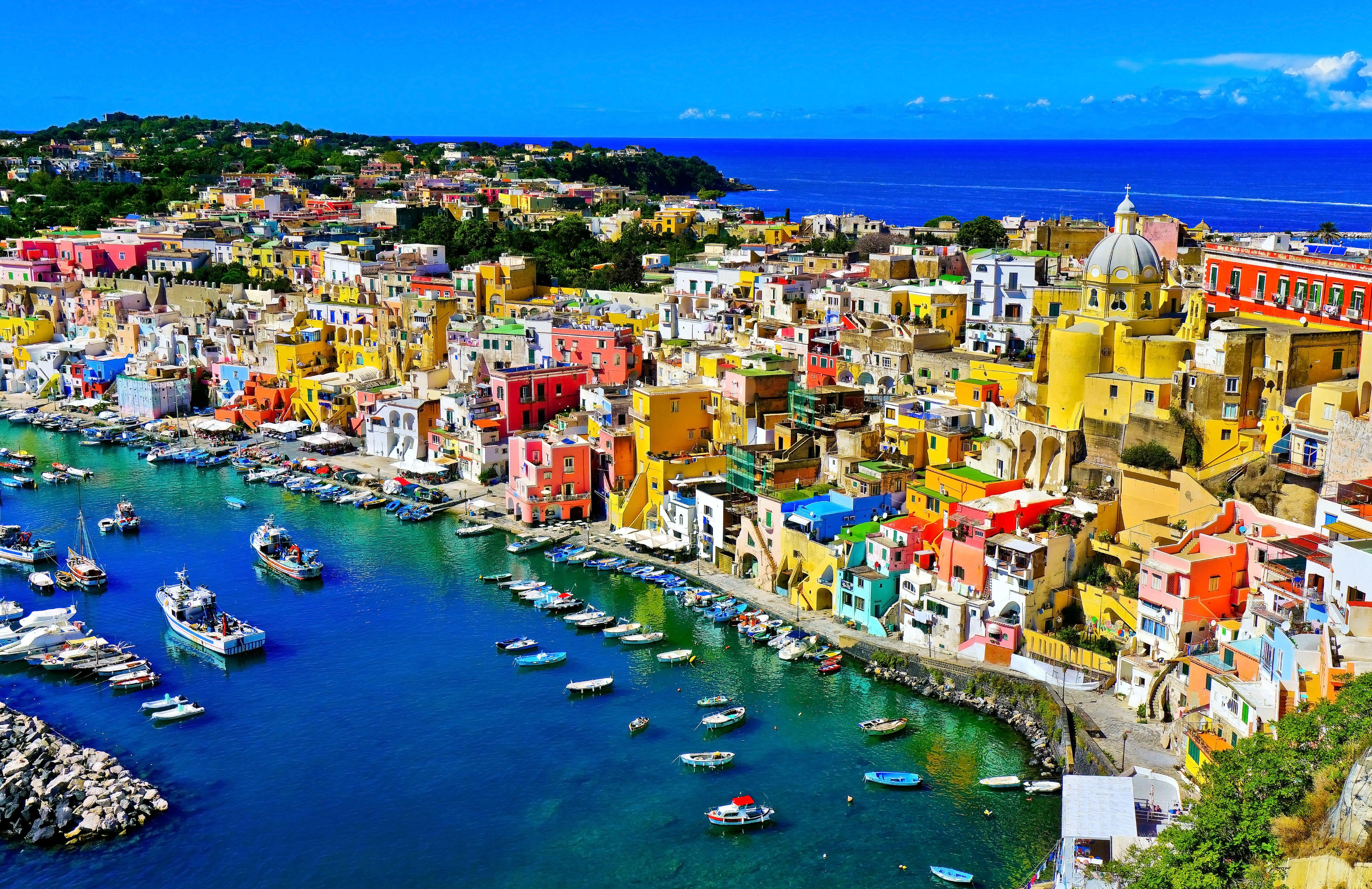 View of the Port of Corricella with lots of colorful houses on a sunny day in Procida Island, Italy.