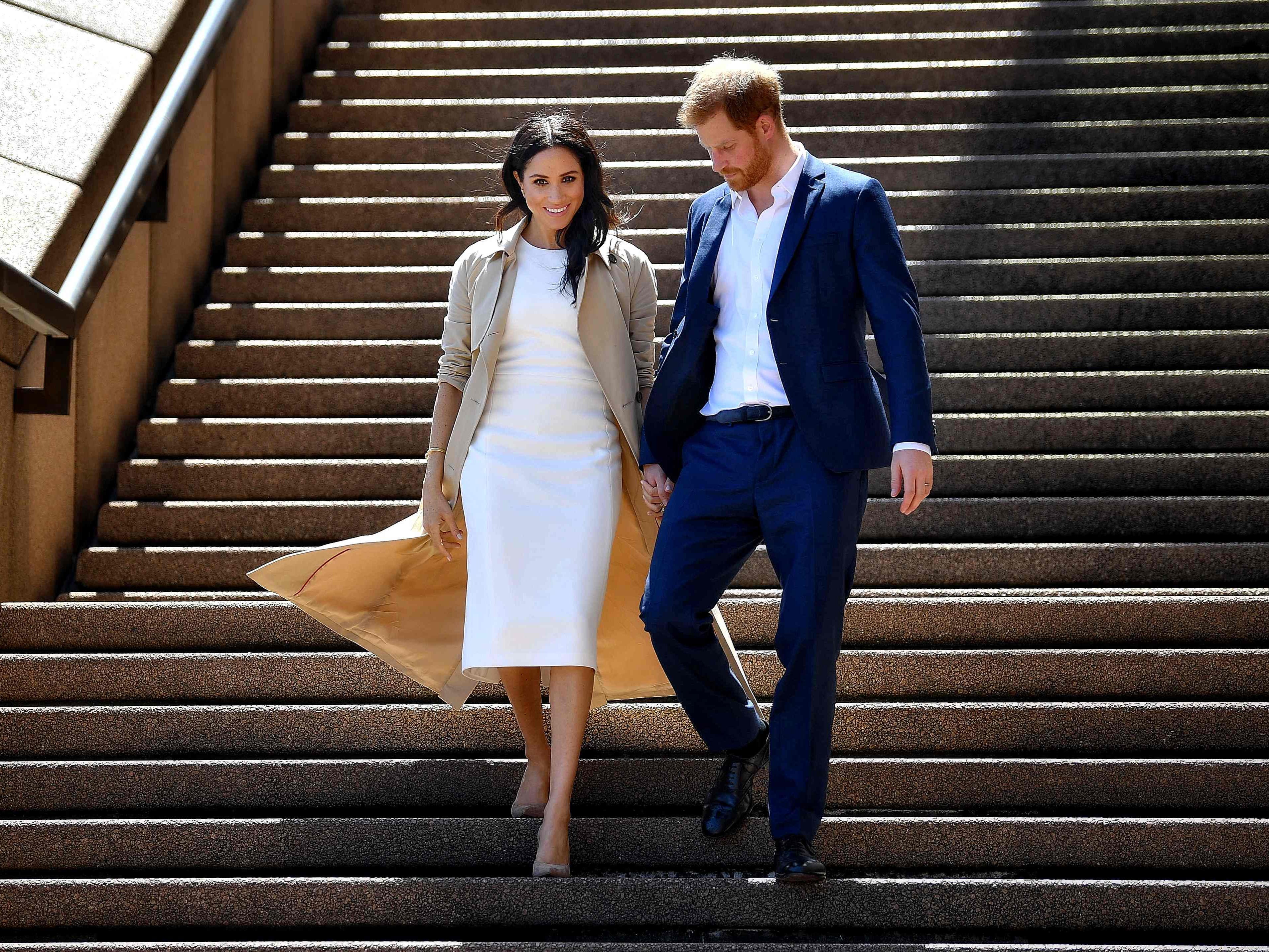 In this file photo taken on October 16, 2018 Britain’s Prince Harry and his wife Meghan walk down the stairs of the iconic Opera House in Sydney.
