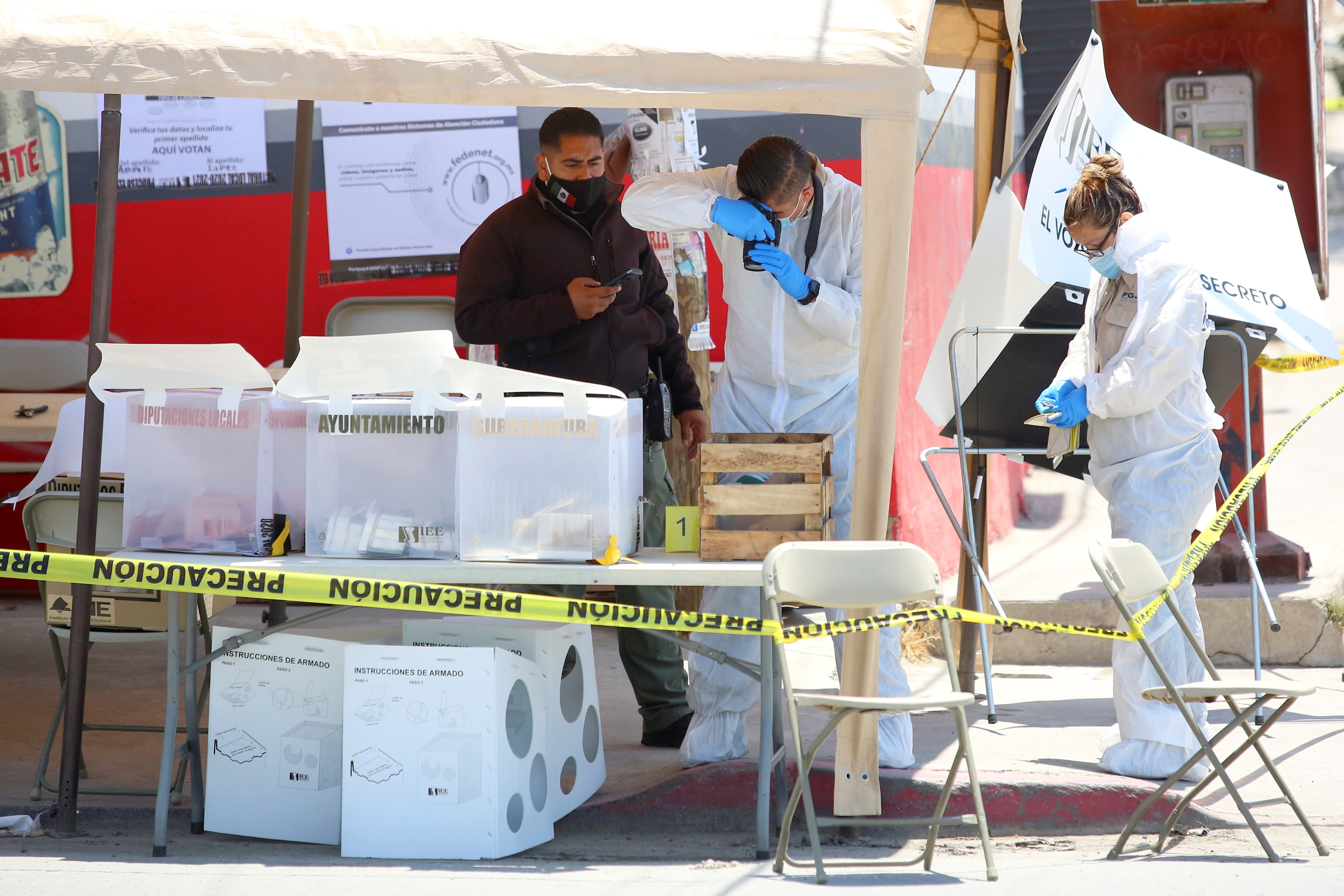 Forensic technicians work at a scene in a polling station where a man threw a severed human head, during the mid-term elections in Tijuana, Mexico