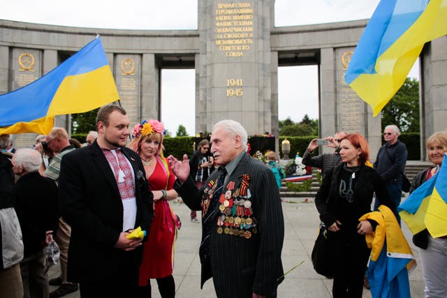<p>File: In this Friday, 8 May 2015 file photo, Soviet war veteran David Dushman, 92, center, speaks to people holding Ukrainian flags as he attends a wreath laying ceremony at the Russian War Memorial in the Tiergarten district of Berlin, Germany</p>