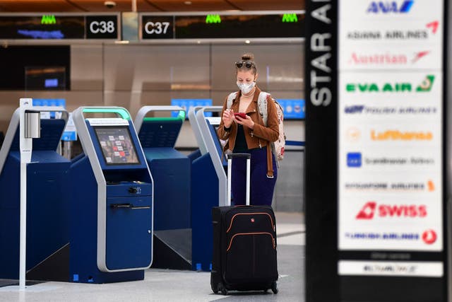 <p>A woman checks her cellphone by self check-in kiosks on the departures level of Los Angeles International Airport (LAX) on May 27, 2021 in Los Angeles.</p>