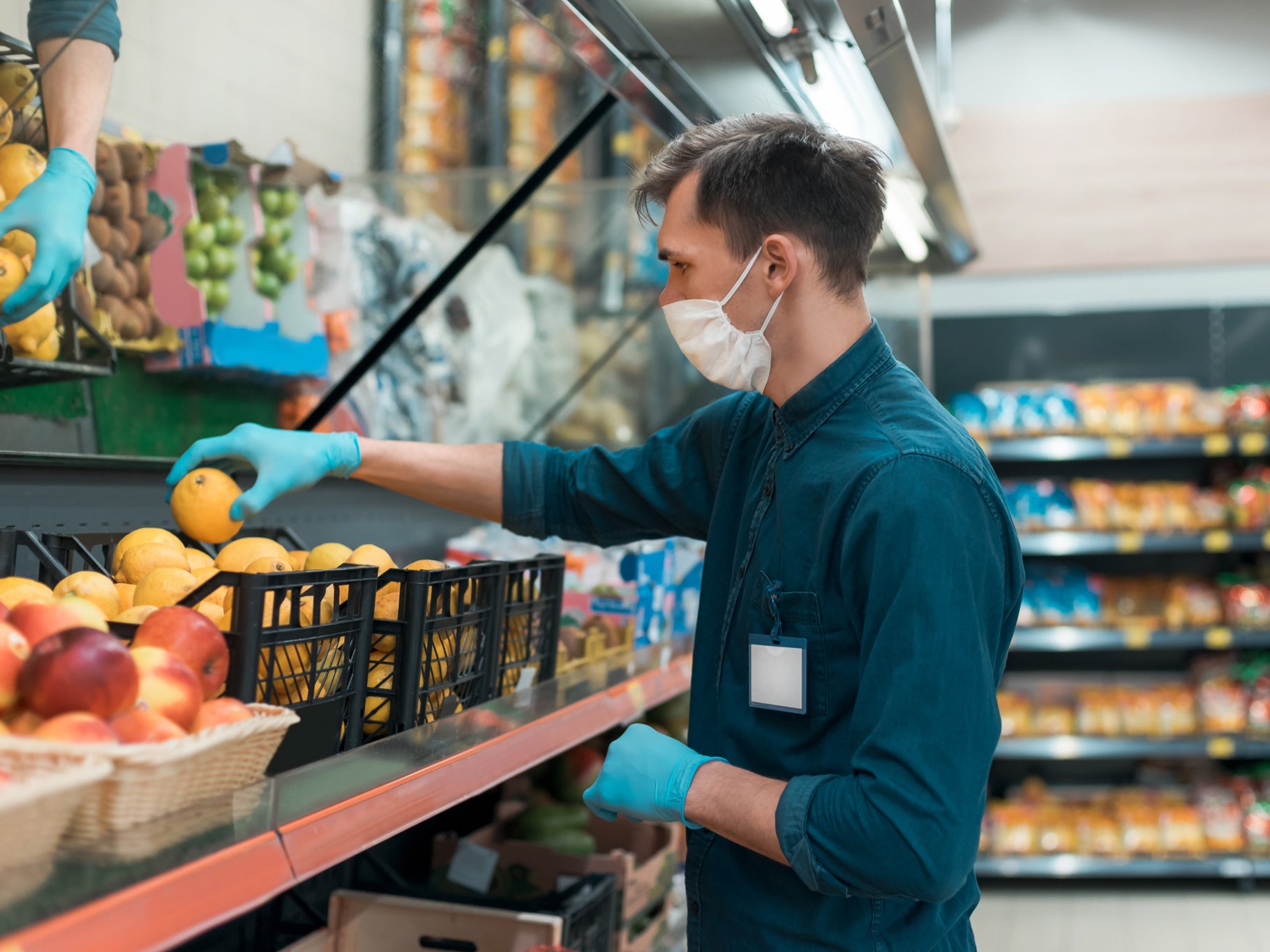 Supermarket worker stocks the fruit counter