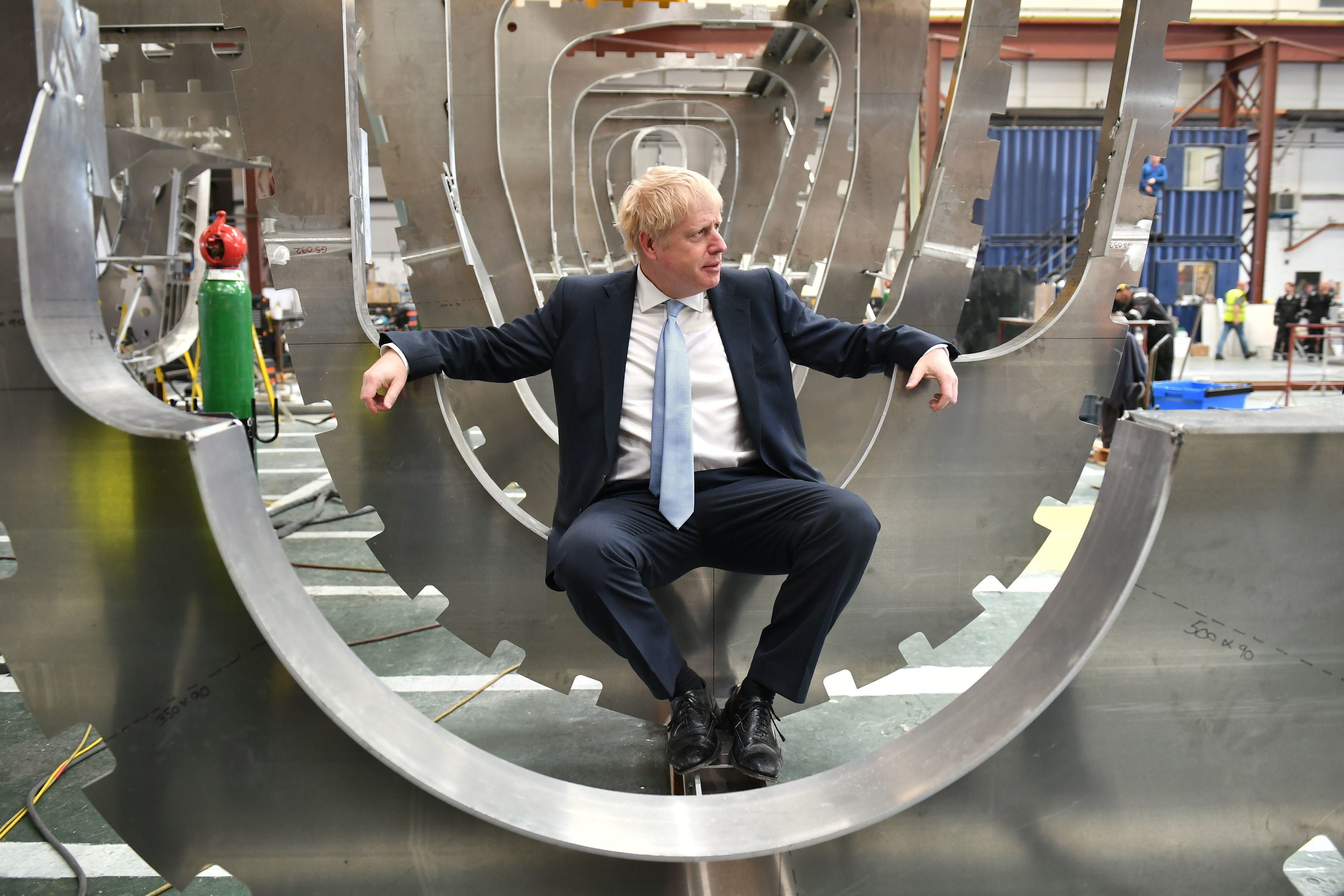 Boris Johnson sits in a boat under construction at the Venture Quay boatyard during a visit to the Isle of Wight on June 27, 2019