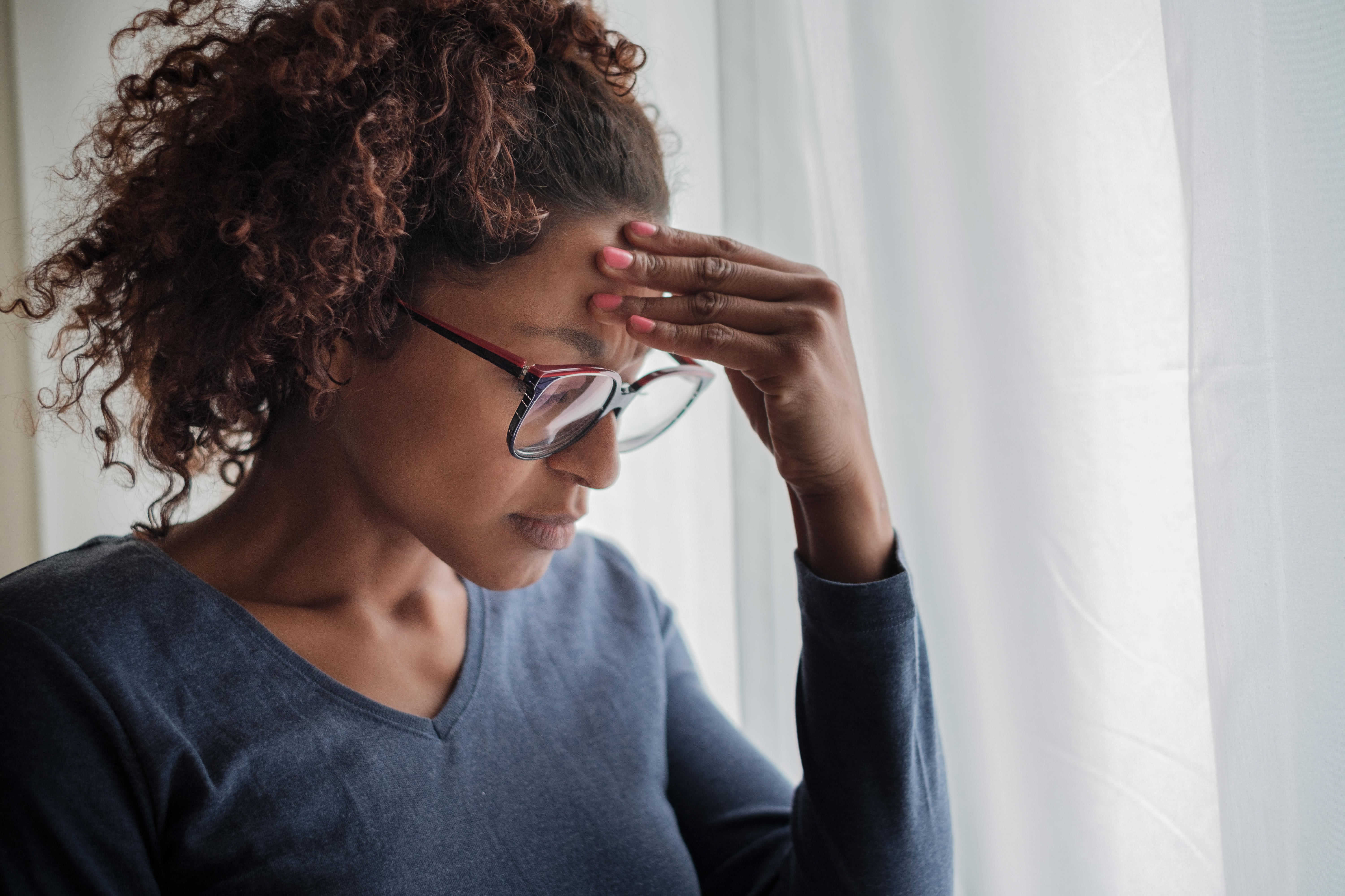 Portrait of pensive black woman standing beside window