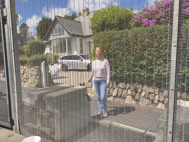 Christine Norton behind security fencing installed across Crabis Bay and St Ives