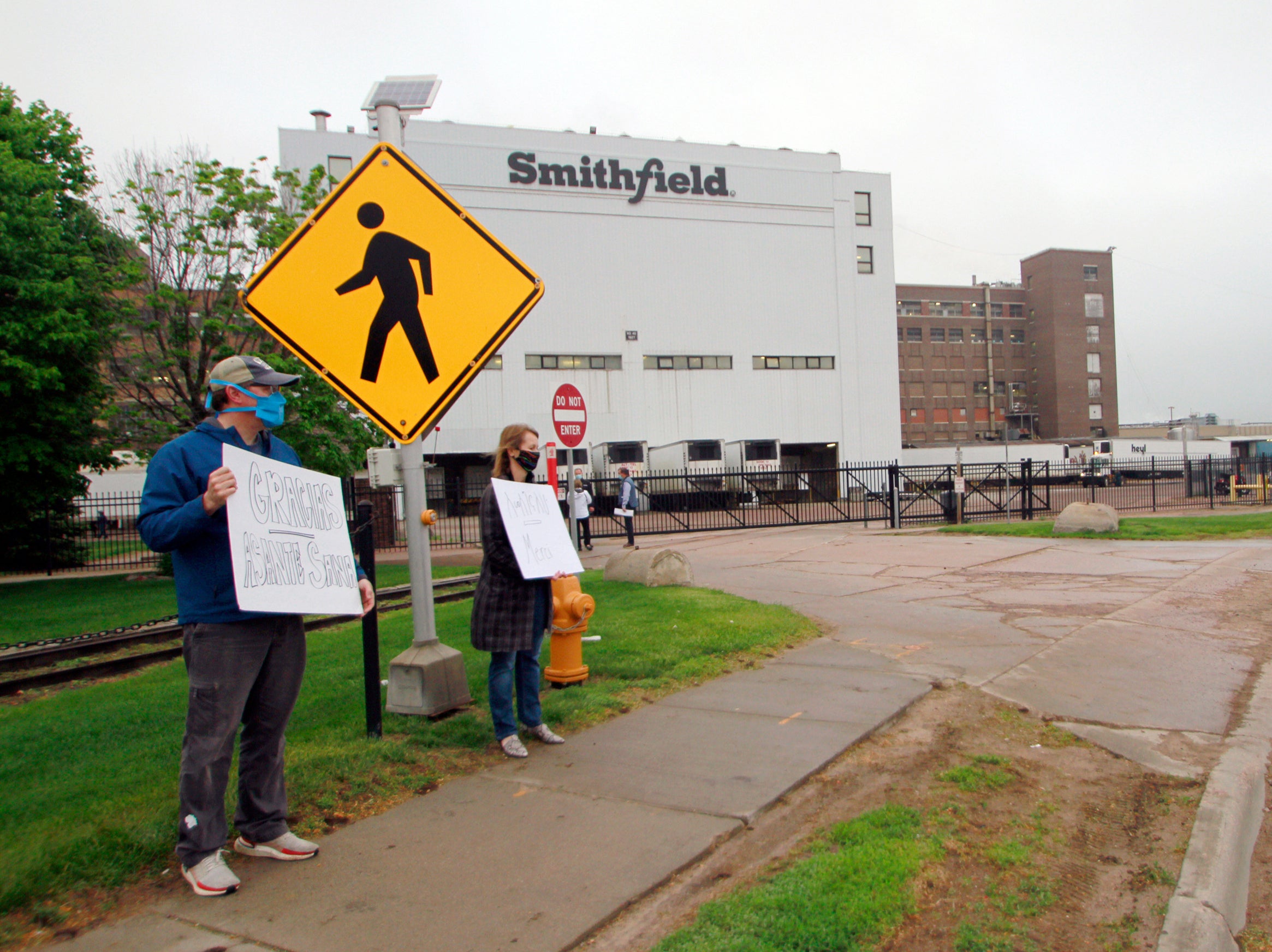 Residents cheer and hold thank you signs to greet employees of a Smithfield pork processing plant as they begin their shift in Sioux Falls, SD