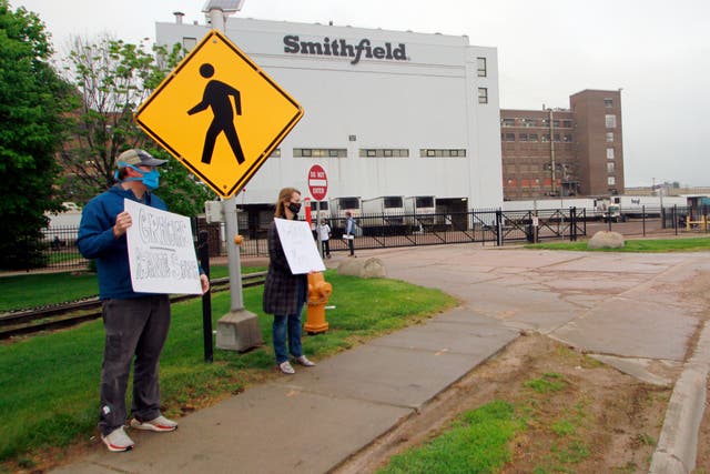 <p>Residents cheer and hold thank you signs to greet employees of a Smithfield pork processing plant as they begin their shift in Sioux Falls, SD</p>