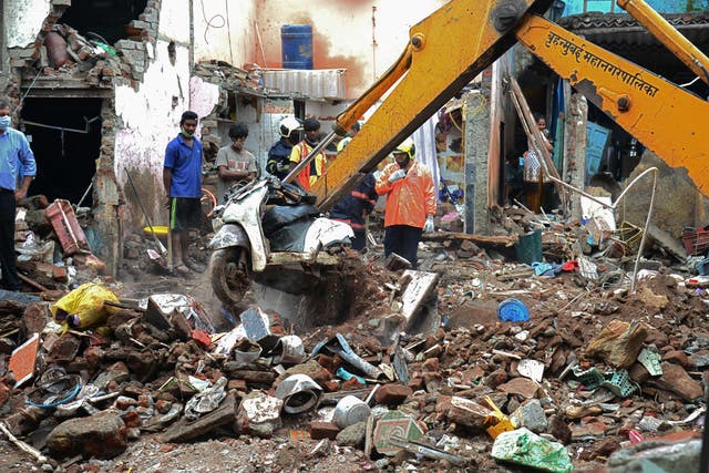 <p>Civil authority and rescue personnel search for survivors in the debris of a building that collapsed following heavy monsoon rains, in Mumbai on 10 June 2021</p>