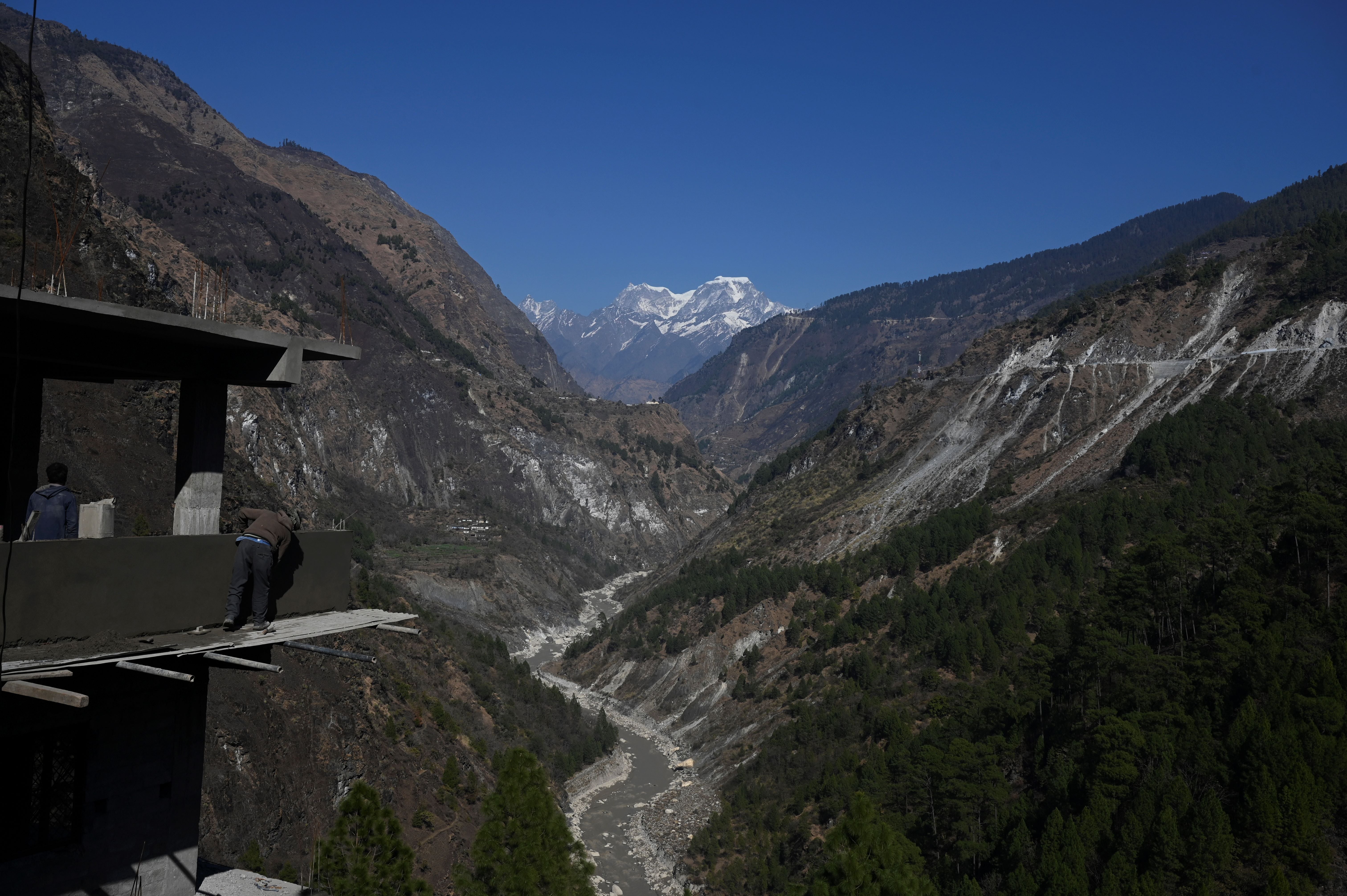 A mason works at an under-construction building site on the edge of the mountain valley in Chamoli district of Uttarakhand