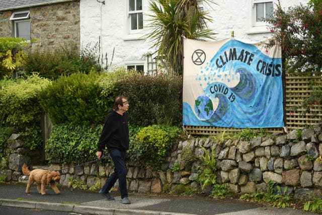 <p>A man walks past a banner displayed on a garden wall in St Ives, Cornwall, ahead of the three-day G7 summit being held from 11-13 June</p>