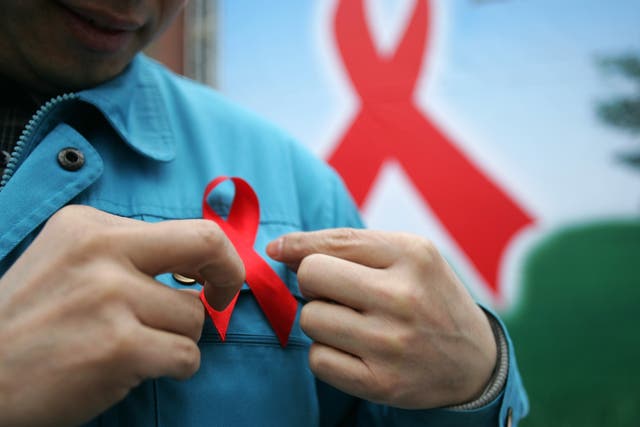 <p>A migrant worker dons a red ribbon during an event to promote HIV/Aids knowledge in China in 2005</p>