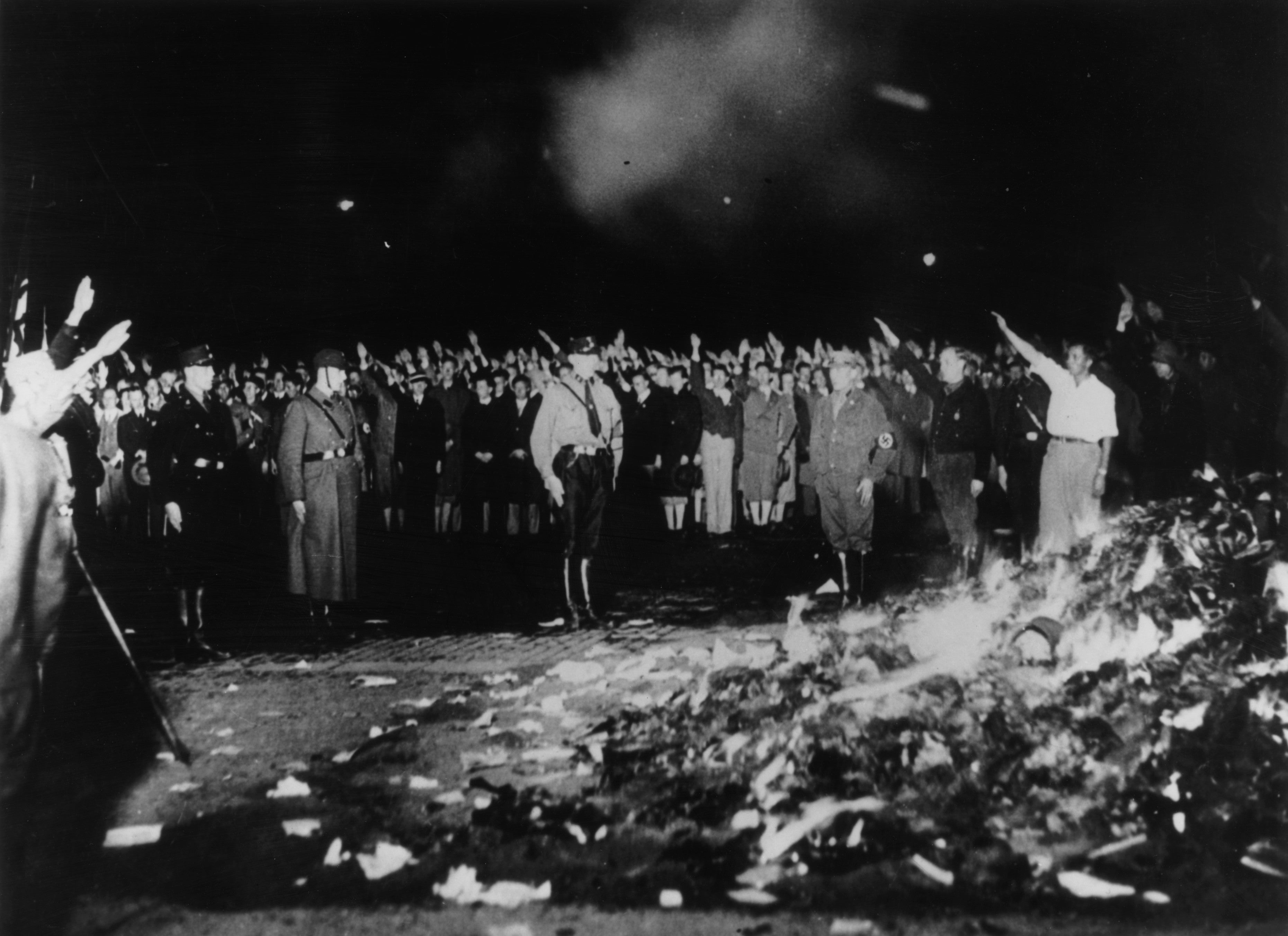 May 1933: German soldiers and civilians give the Nazi salute as thousands of books smoulder during one of the mass book-burnings implemented throughout the country to destroy non-Aryan publications