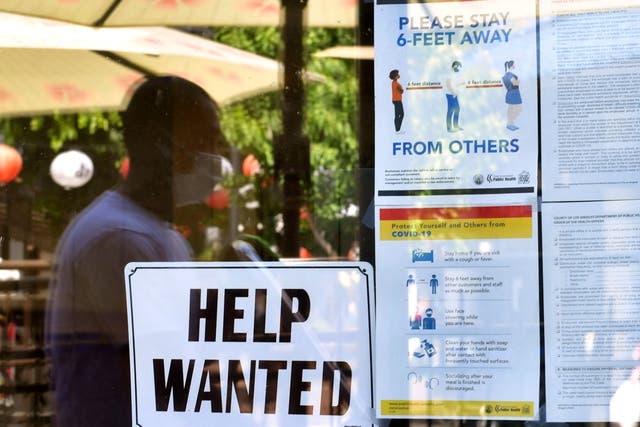 <p>A ‘Help Wanted’ sign is posted beside Coronavirus safety guidelines in front of a restaurant in Los Angeles, California on 28 May 2021</p>