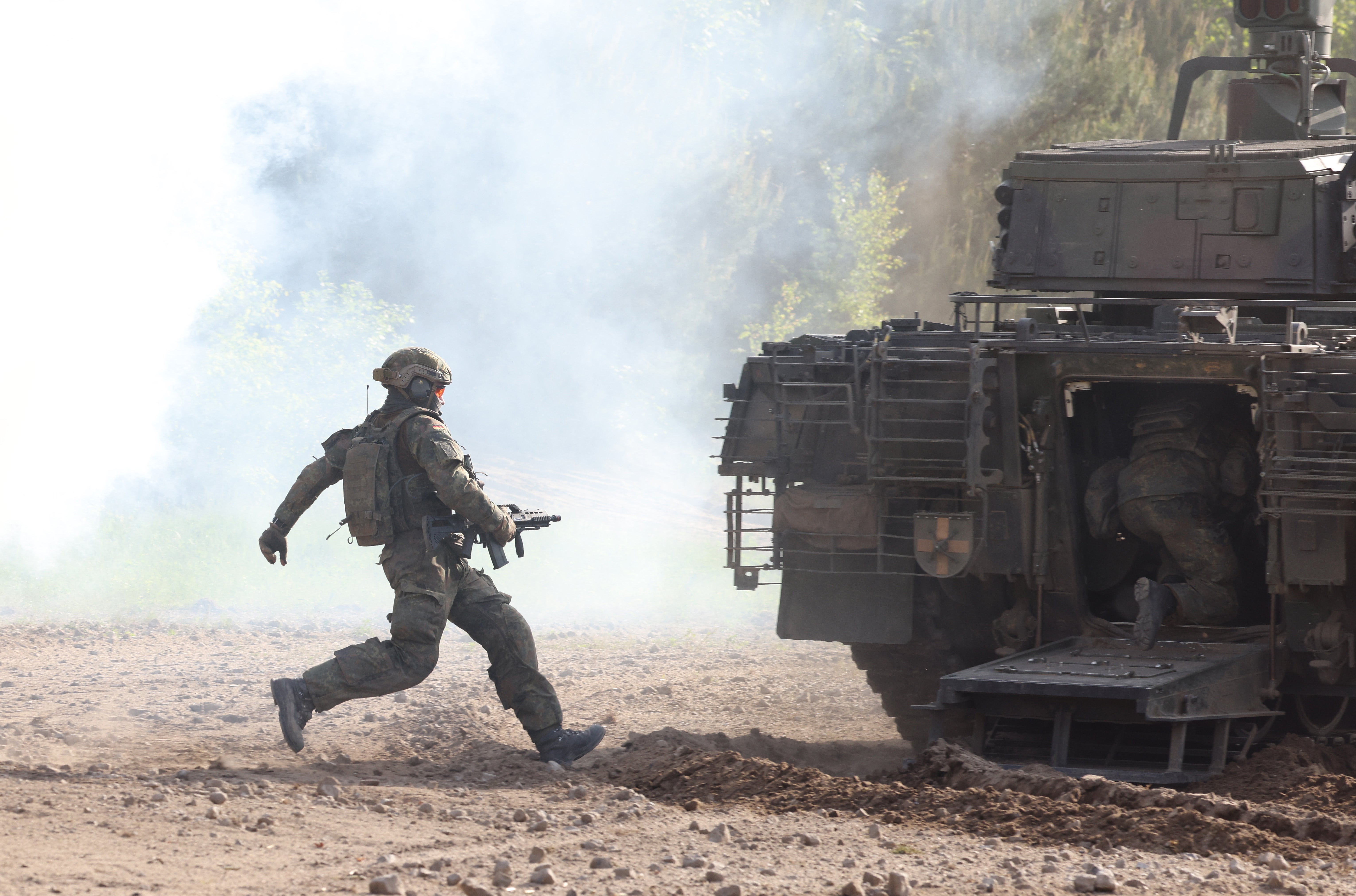 A Bundeswehr soldier runs towards a Puma mechanized infantry combat vehicle during a demonstration of capabilities by the Panzerlehrbrigade 9 tank training brigade on June 02, 2021 in Munster, Germany. Germany has steadily increased its defense spending in recent years, to a record EUR 53 billion slated for 2021