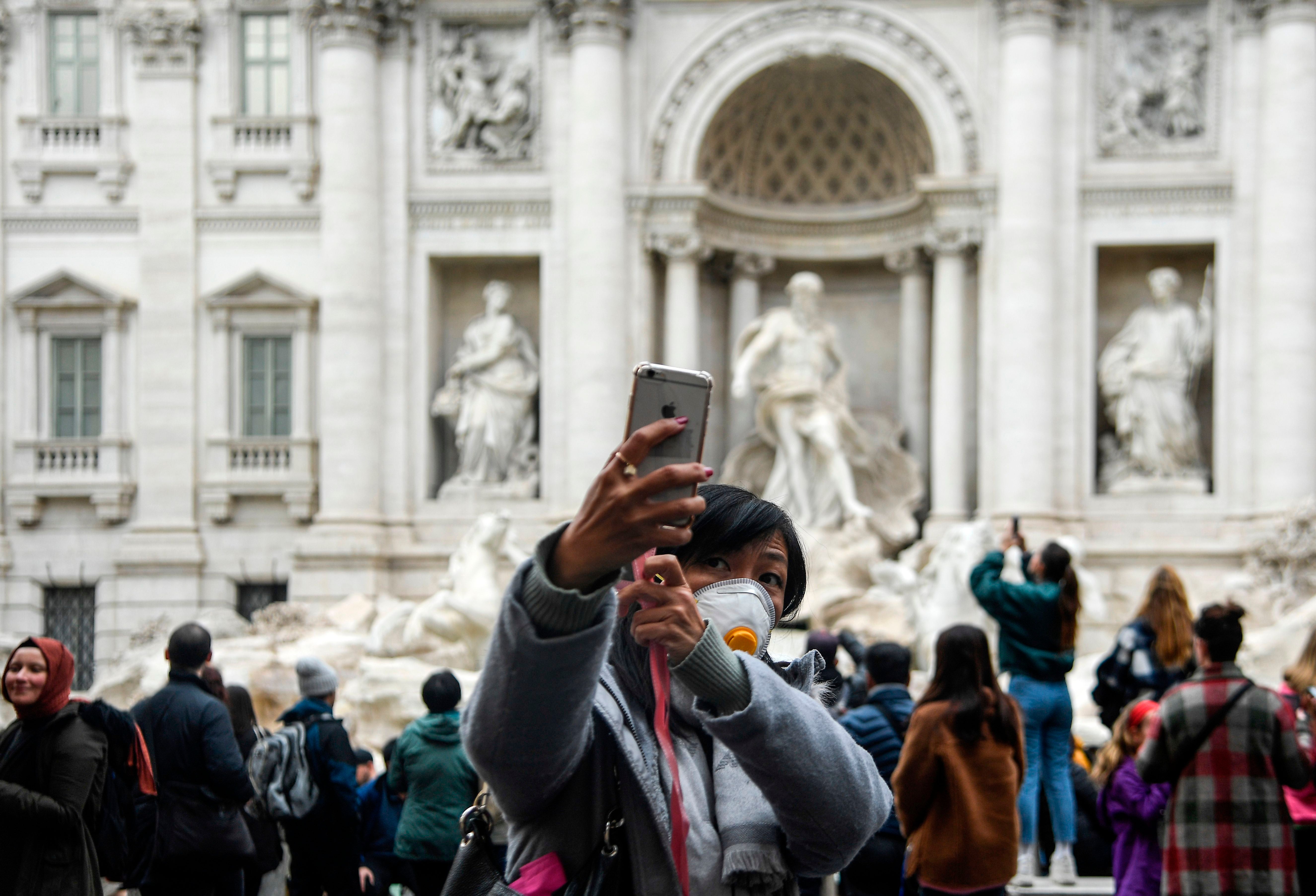 Tourists take selfies by the Trevi Fountain in downtown Rome