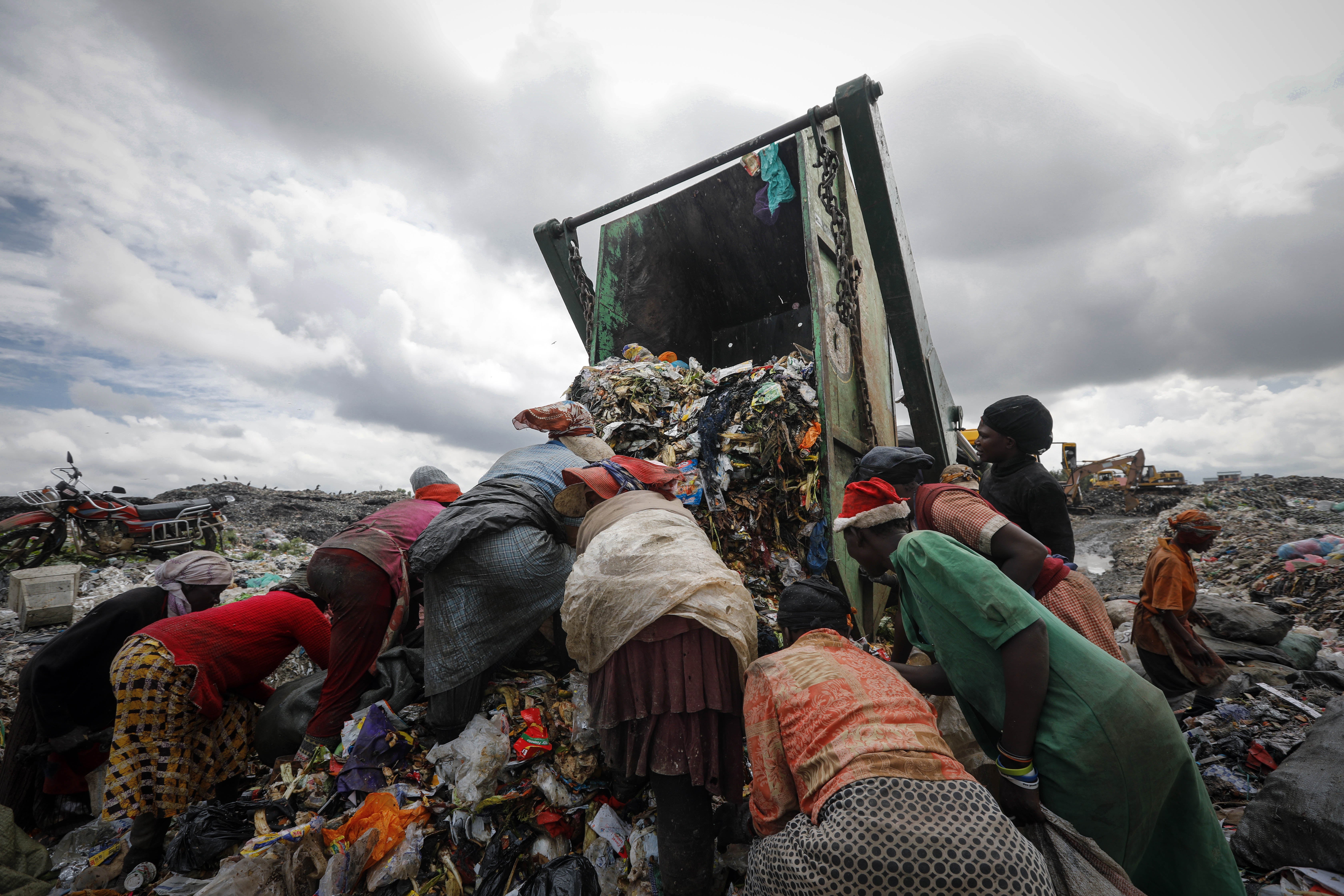 Women gather around a truck full of rubbish in Kenya to find valuable parts to sell