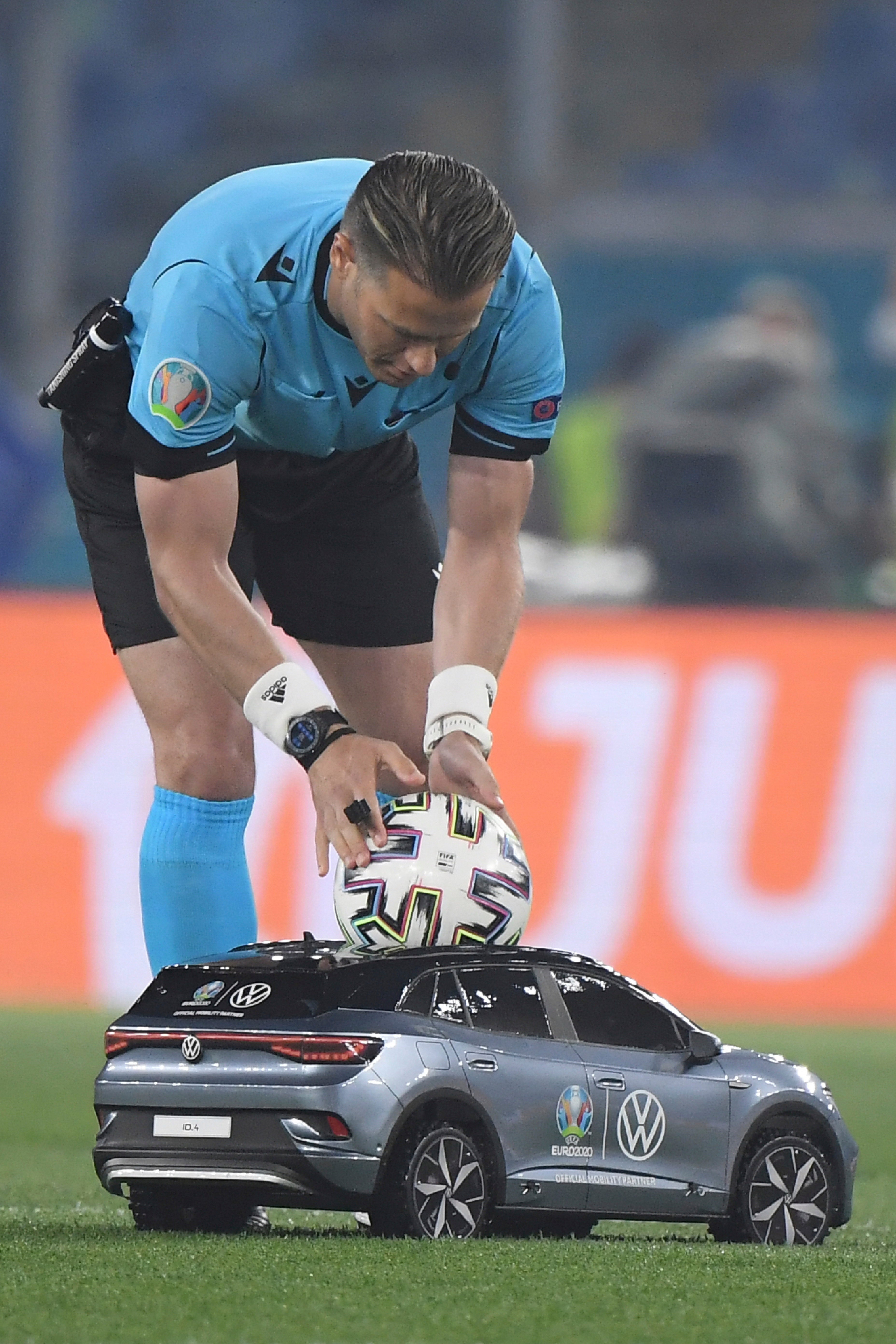 Dutch referee Danny Makkelie picks up the match ball, which was delivered by a remote-controlled car