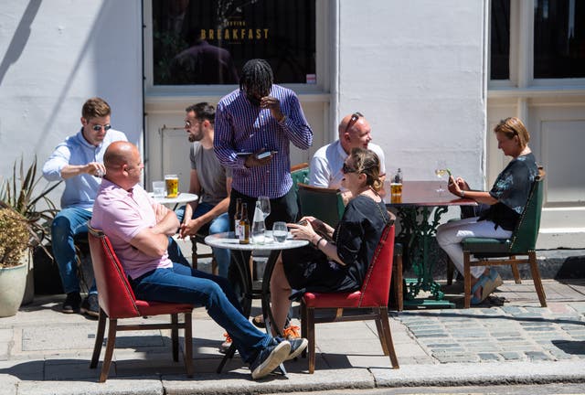 People eat and drink at tables outside a pub