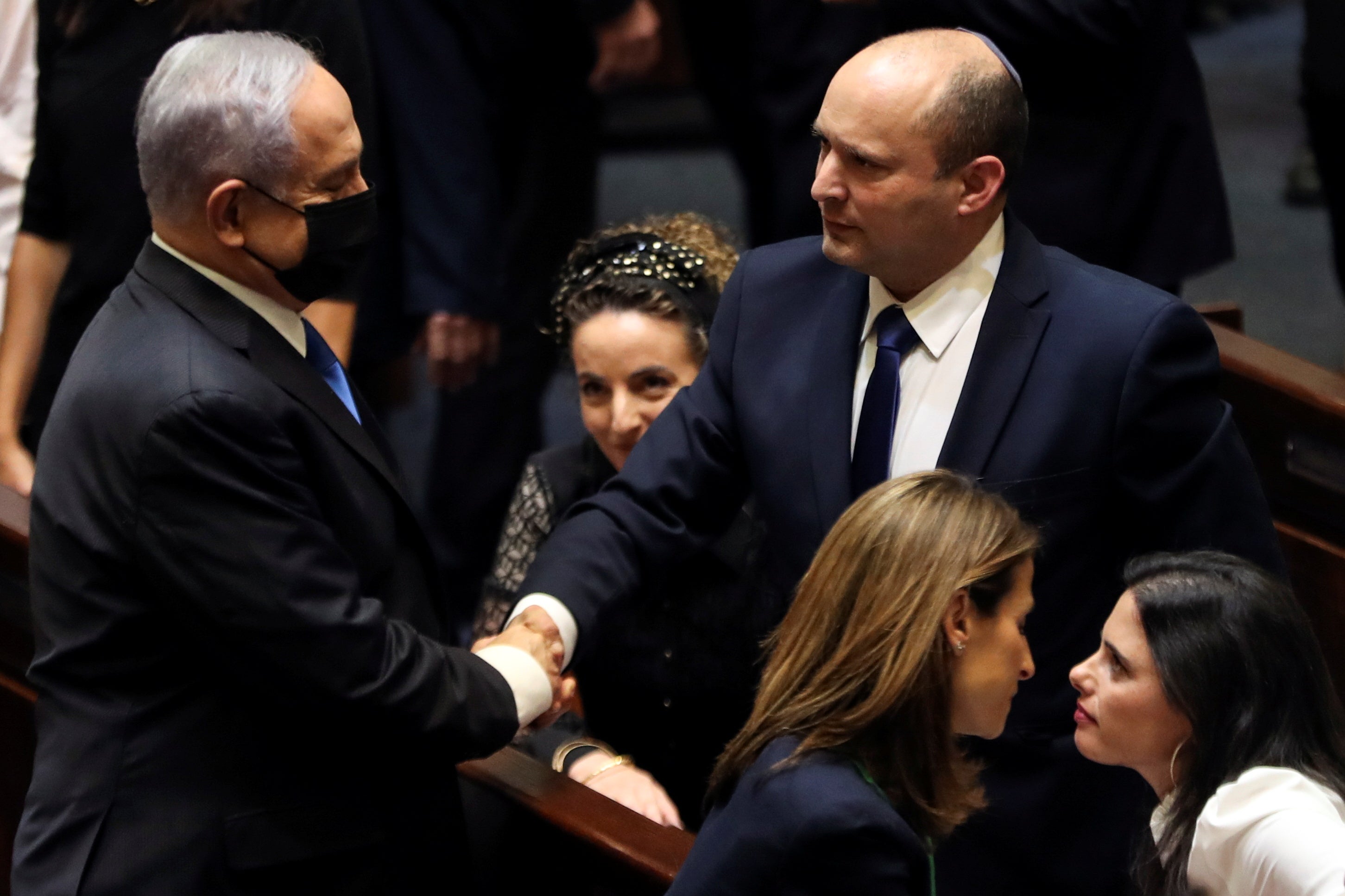 <p>Benjamin Netanyahu shakes hands with the man who has replaced him as Israel Prime Minister, Naftali Bennett, following the vote on the new coalition at the Knesset, Israel’s parliament</p>