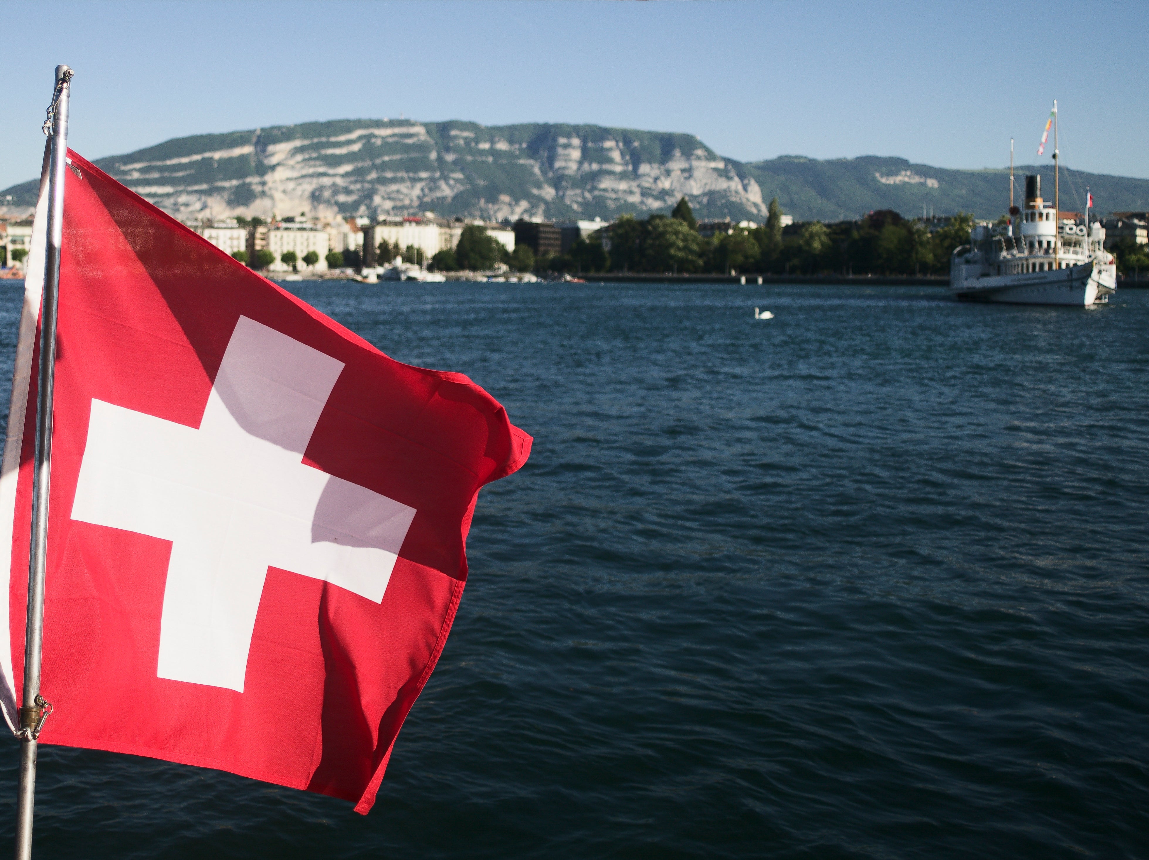 <p>The Swiss national flag flutters over Lake Geneva in Switzerland</p>