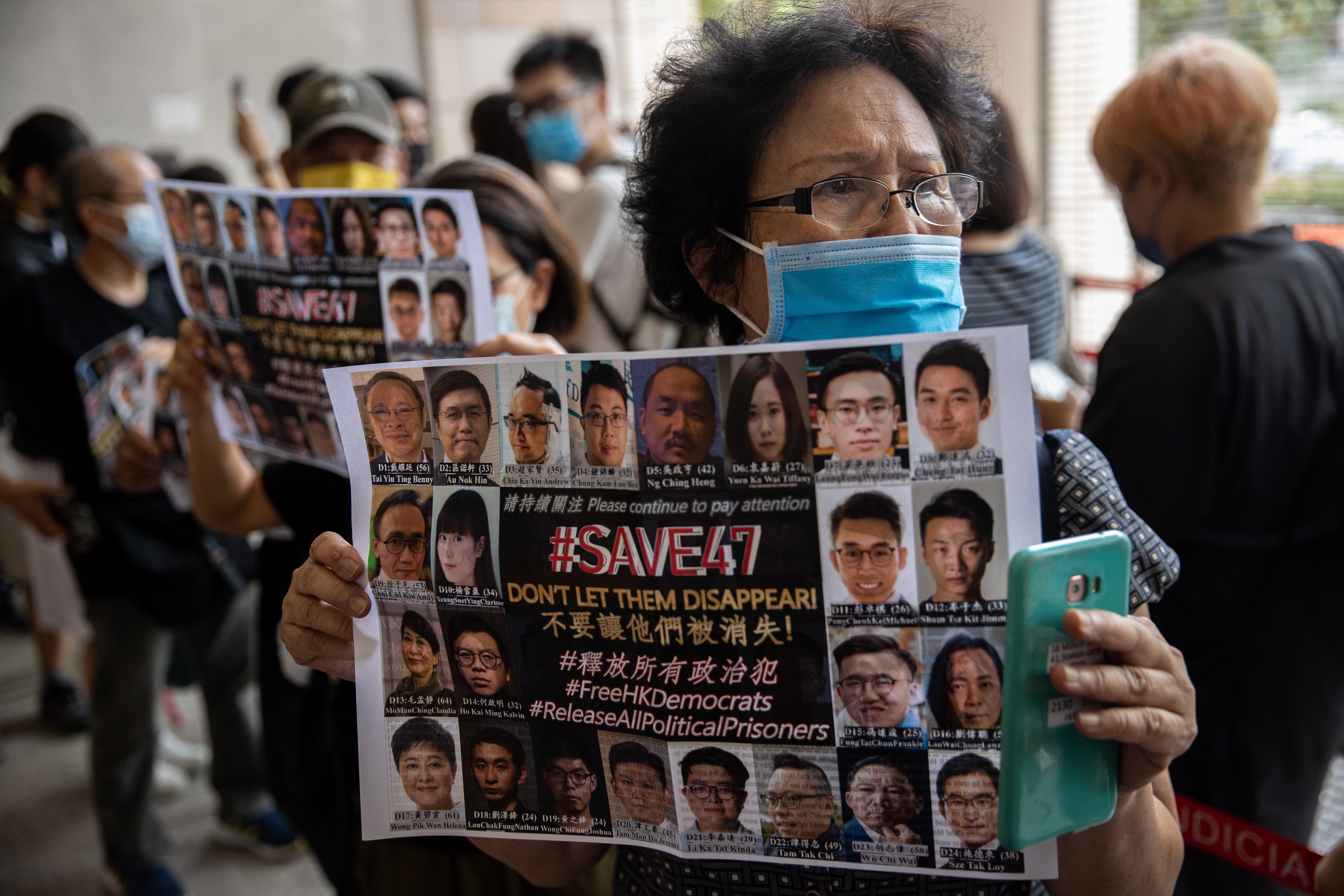 A supporter holds a poster of pro-democracy figures on trial under the new national security law