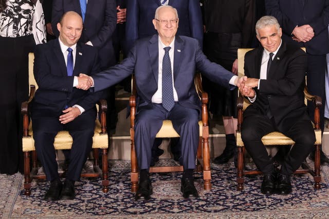 <p>Israel's President Reuven Rivlin between Prime Minister Naftali Bennett and Foreign Minister Yair Lapid as they pose for a group photo with ministers of the new Israeli government</p>