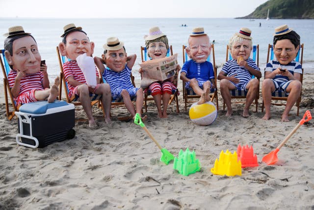 <p>Oxfam activists wearing papier mache heads representing G7 leaders perform during a protest near Falmouth</p>