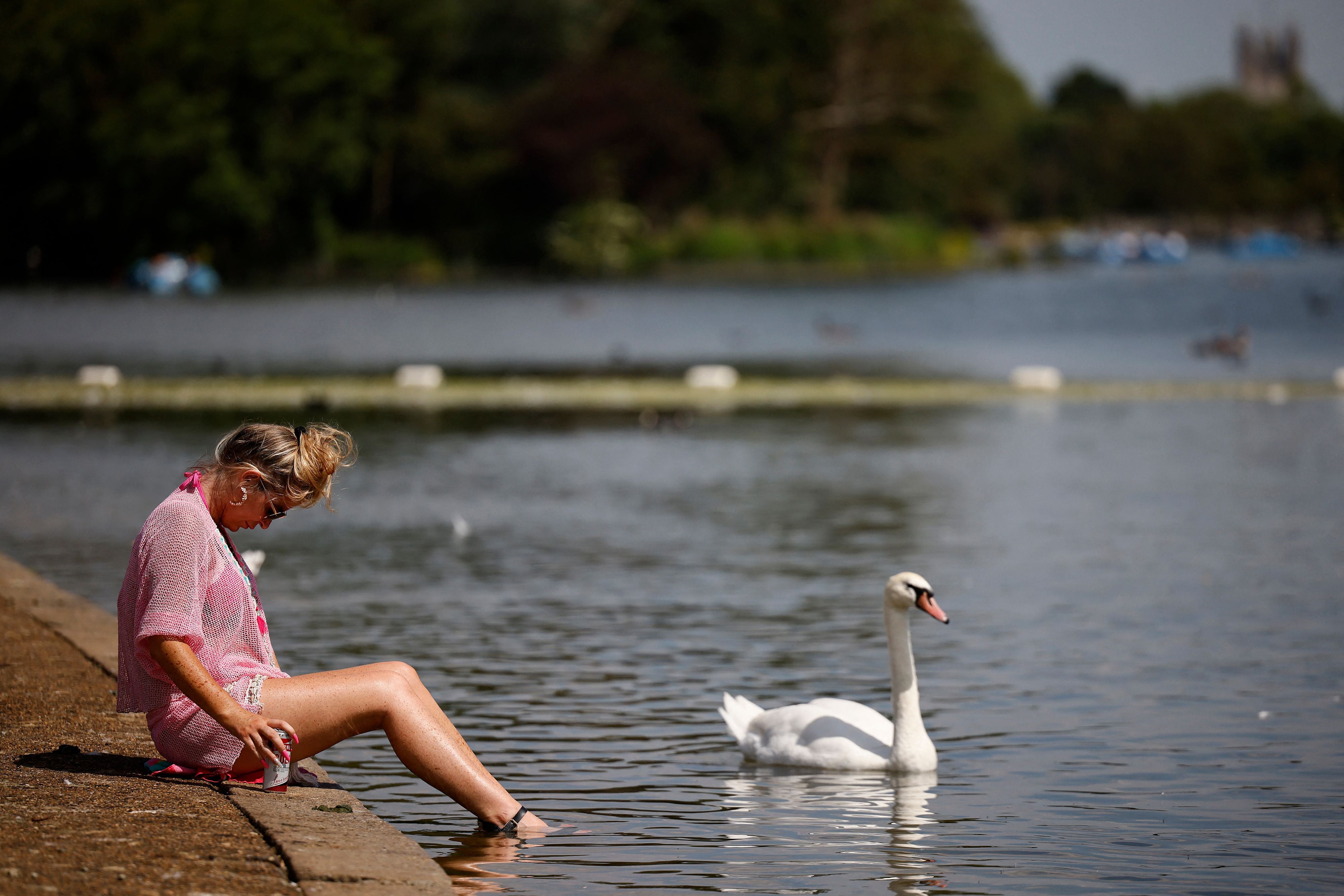 A woman paddles her feet in Serpentine lake in Hyde Park