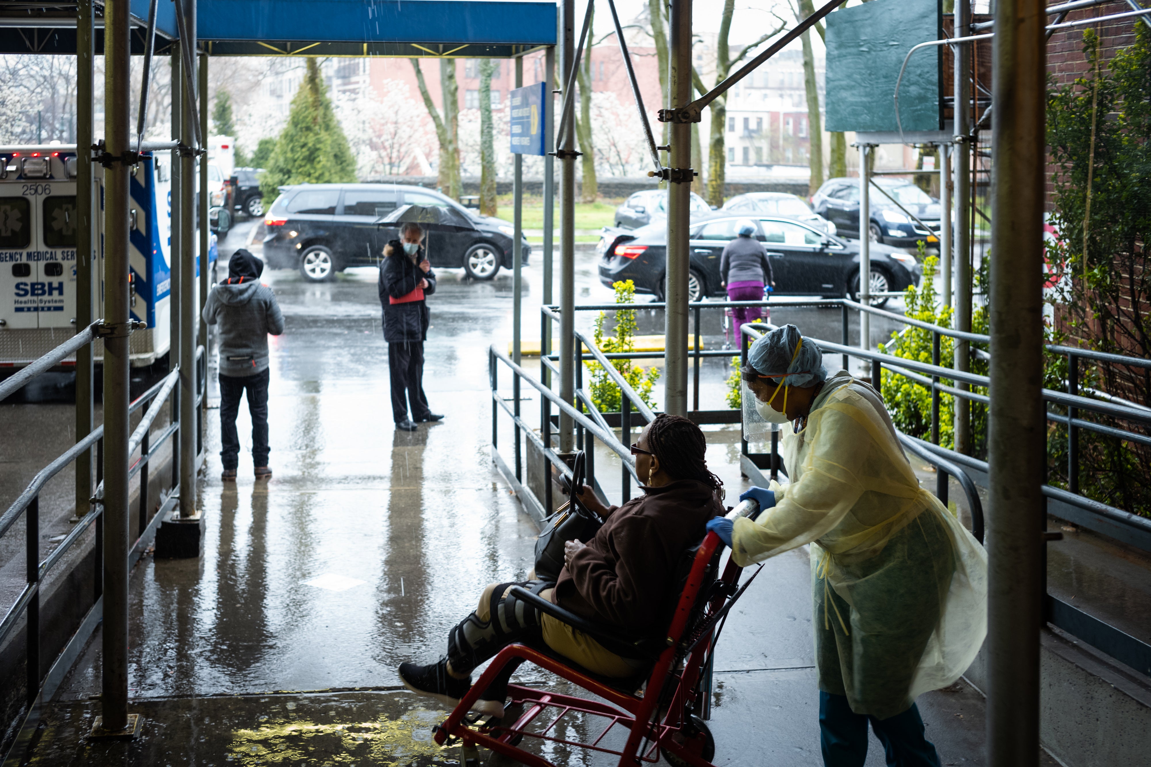 A staff member pushes a patient in a wheelchair at St Barnabas Hospital on 23 March, 2020 in the Bronx borough of New York City.