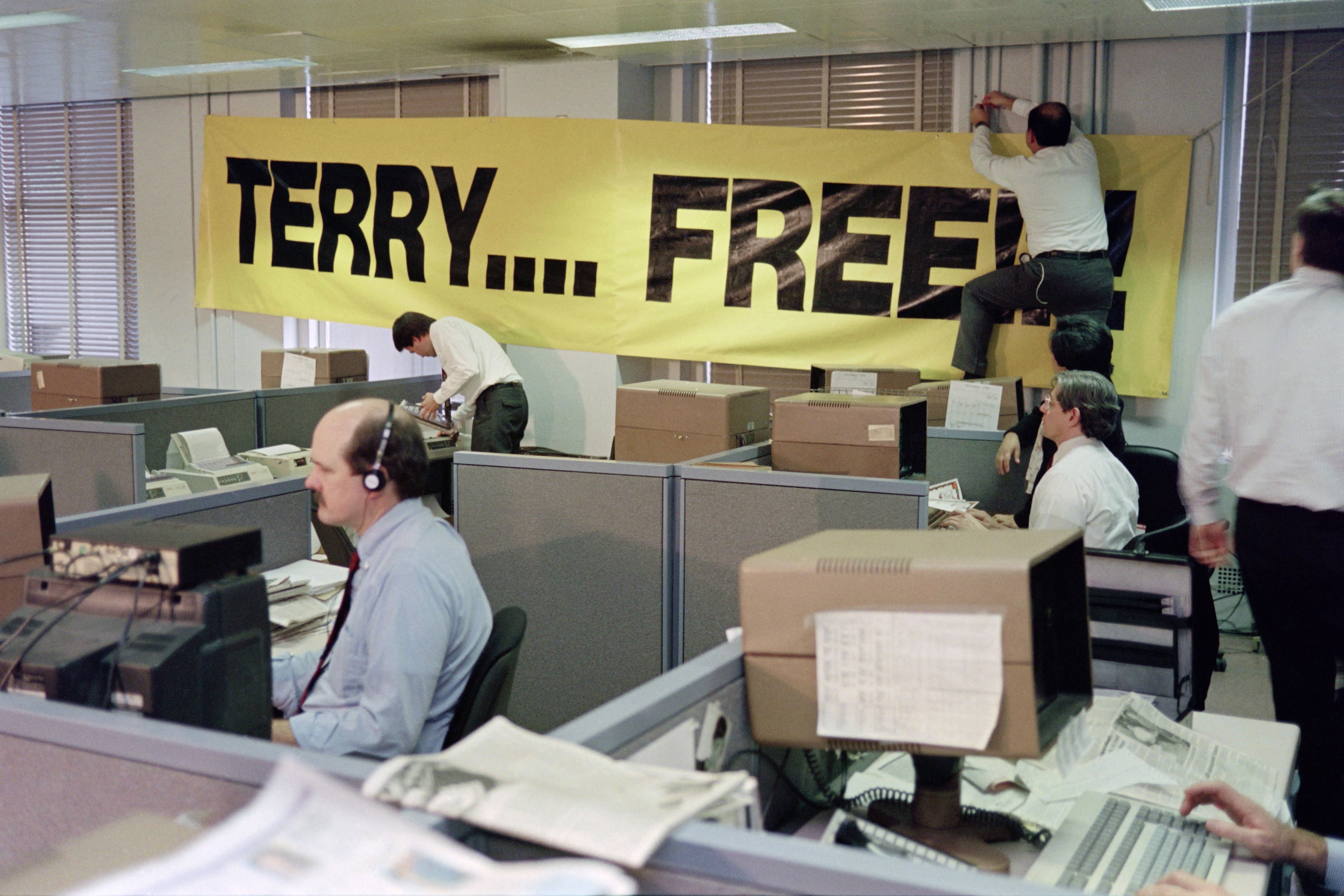Employees at Associated Press headquarters in New York hang a banner in the newsroom as they wait for freed hostage Terry Anderson on 4 December 1991
