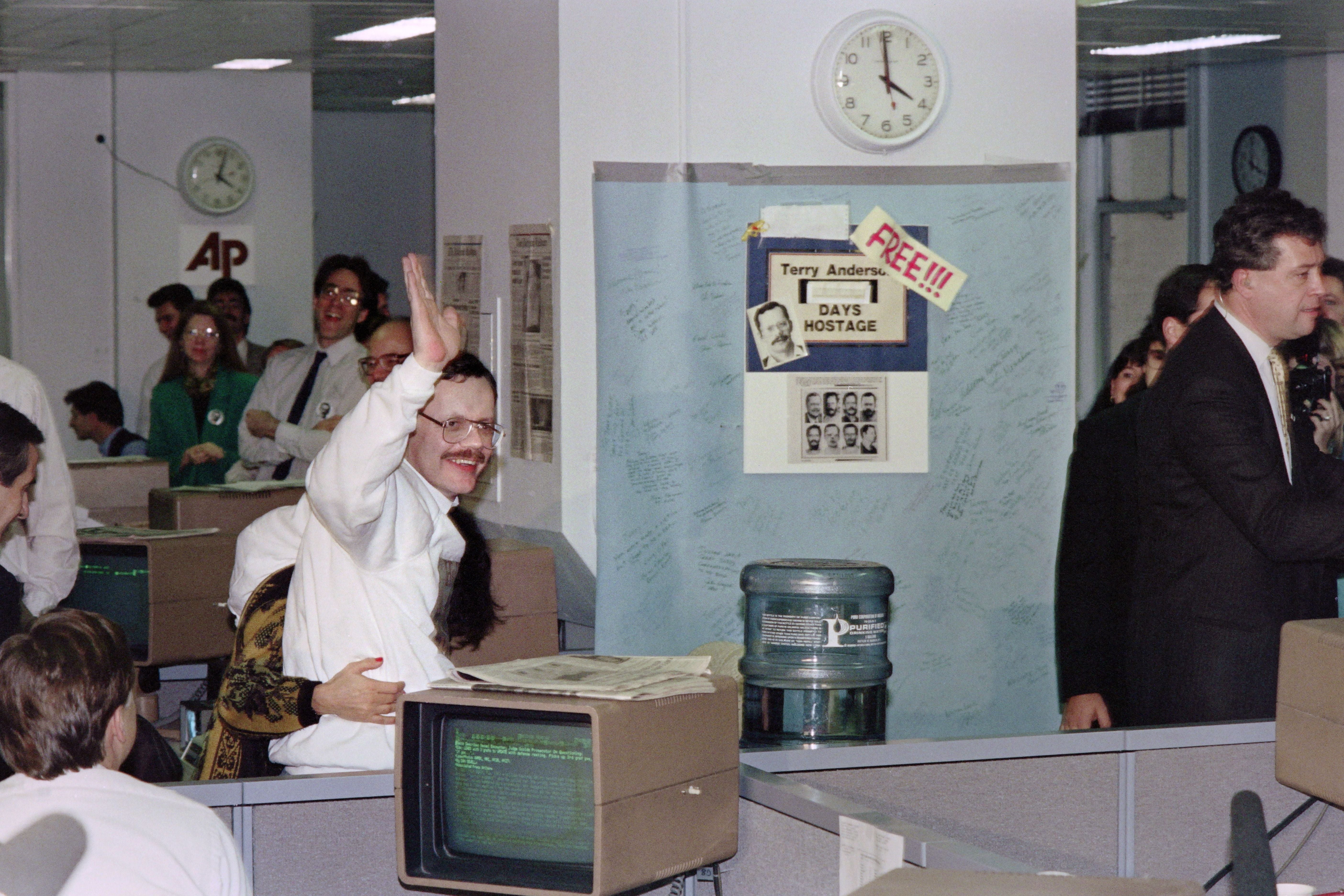 Anderson waves near a sign that marked every day of his captivity, at the AP headquarters in New York, 10 December 1991