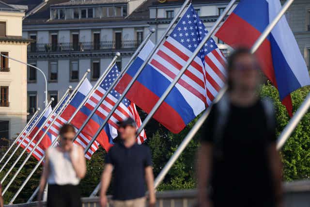 <p>People walk under Russian and American flags on a bridge in Geneva prior to the meeting between Joe Biden and Russian Vladimir Putin</p>