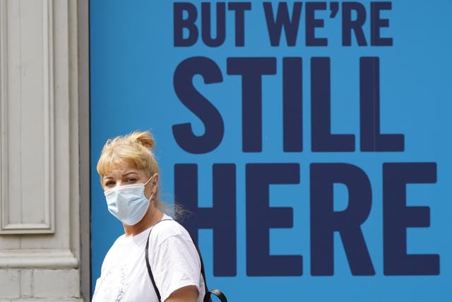 A woman wearing a mask walks past an advert outside Curry’s PC World