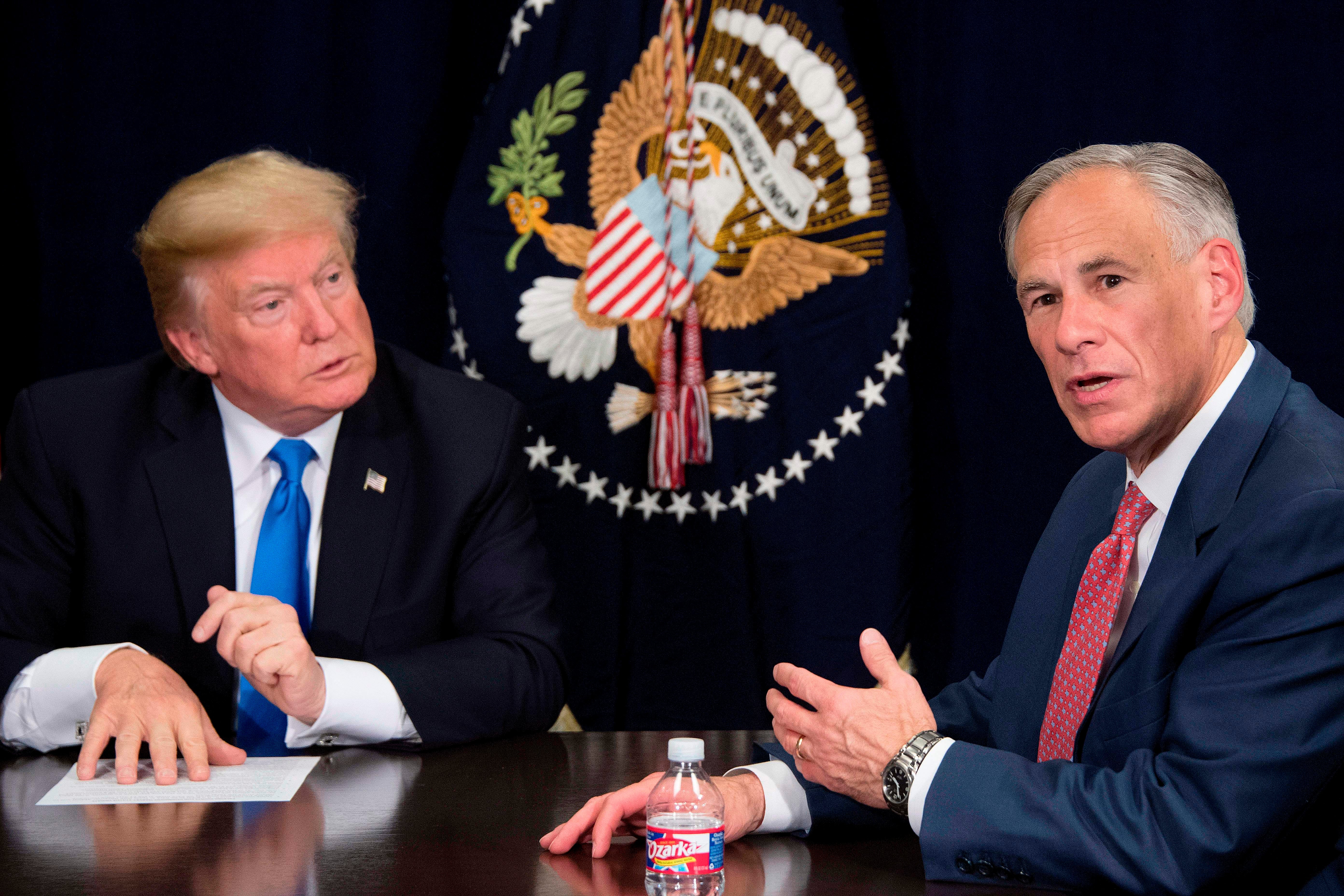 Texas Governor Greg Abbott (right) speaks with then-US President Donald Trump (left) during a briefing on hurricane relief efforts in Dallas, Texas, on 25 October, 2017. Mr Abbott has said he plans to raise funds to build more border wall between the US and Mexico.