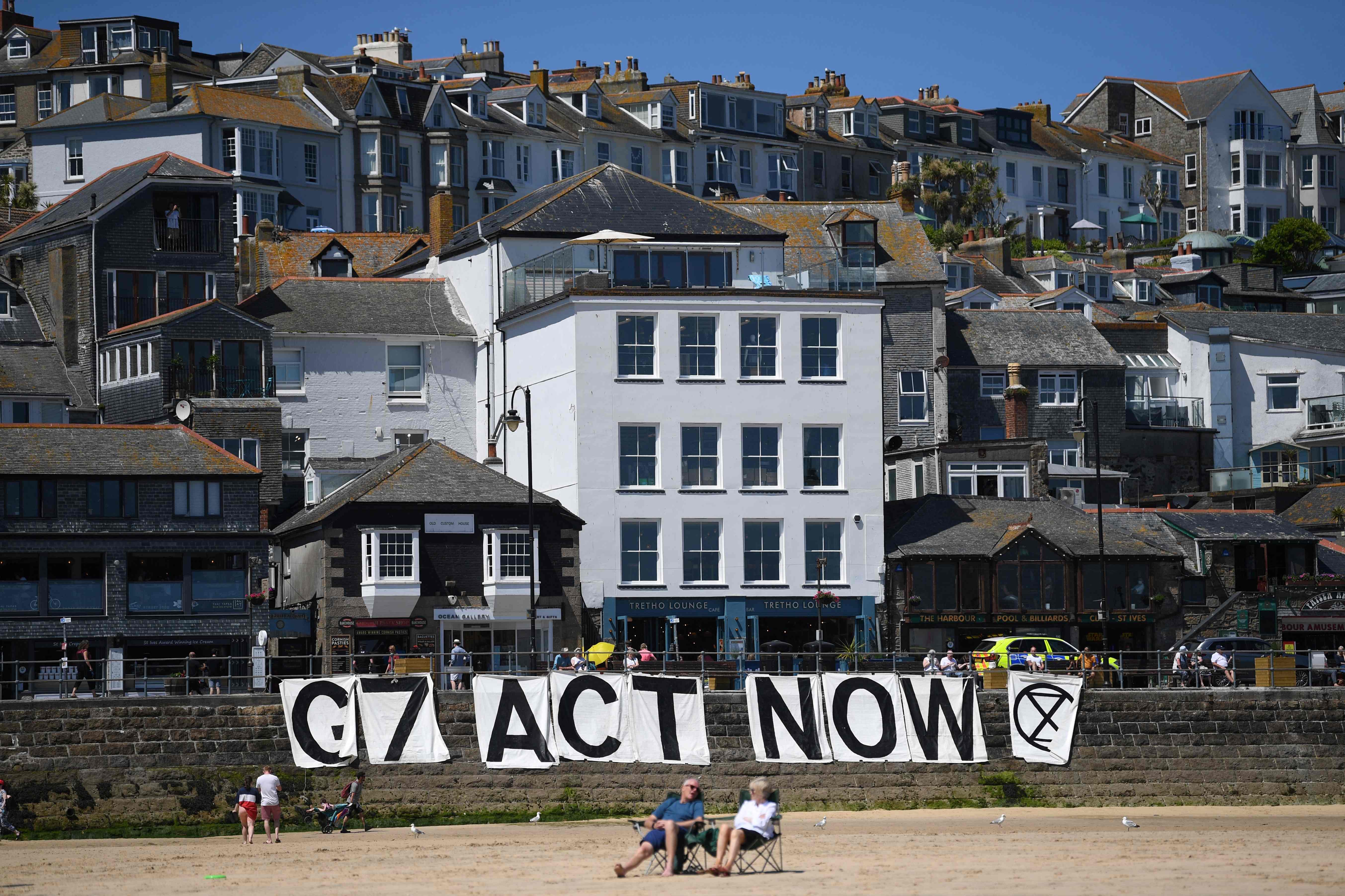 Extinction Rebellion environmental activists attach a banner calling on G7 leaders to act on climate change on the beach in St Ives, Cornwall during the G7 summit on June 13, 202