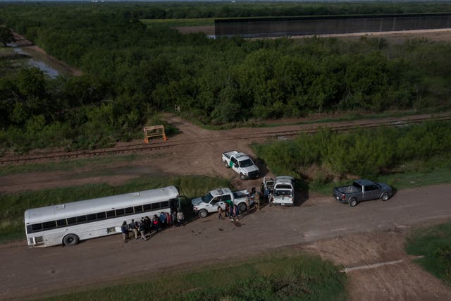 <p>File image: Part of an incomplete border wall is seen in the background as asylum-seeking migrants from Central America line-up outside of a US board patrol bus after crossing the Rio Grande river into the United States from Mexico in La Joya, Texas, US, 20 May, 2021</p>