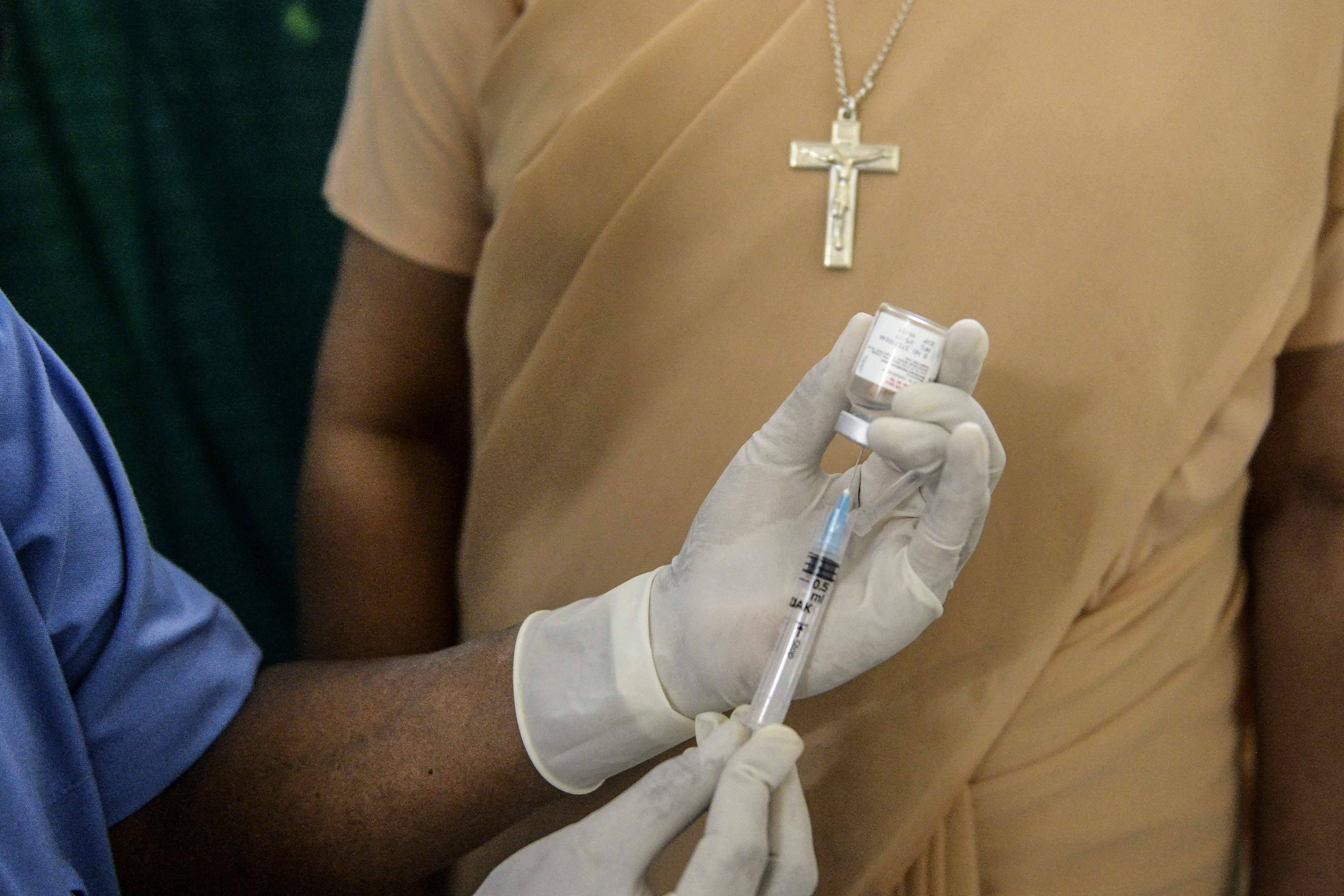 A health worker prepares to inoculate a nun with a dose of the ‘Covaxin’ vaccine against Covid-19