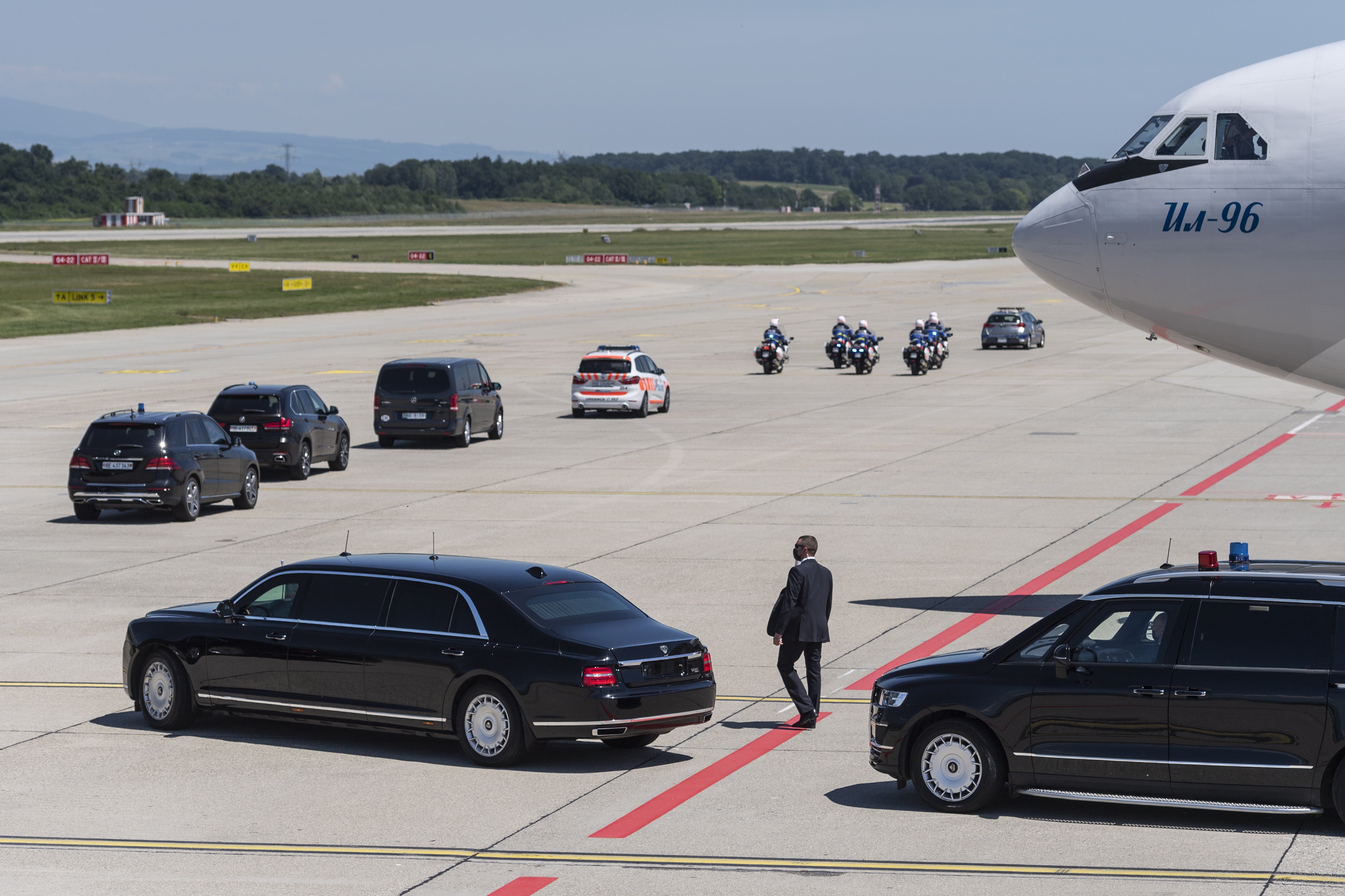 The limousine carrying Russian president Vladimir Putin, bottom left, next to Putin's Iljuschin Il-96 airplane, leaves the airport in a motorcade ahead of the US - Russia summit