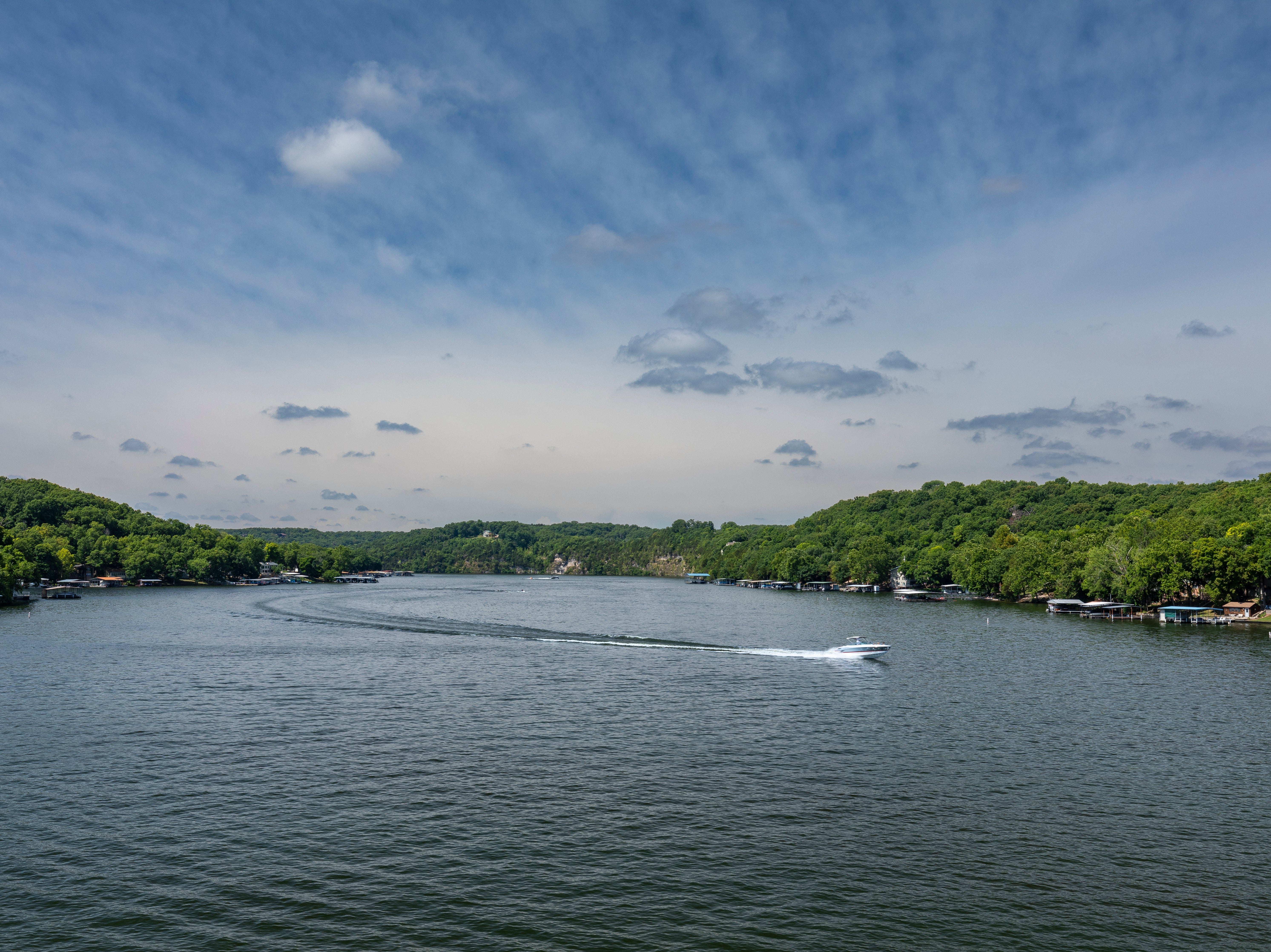 <p>A scenic lake landscape with a speeding boat</p>