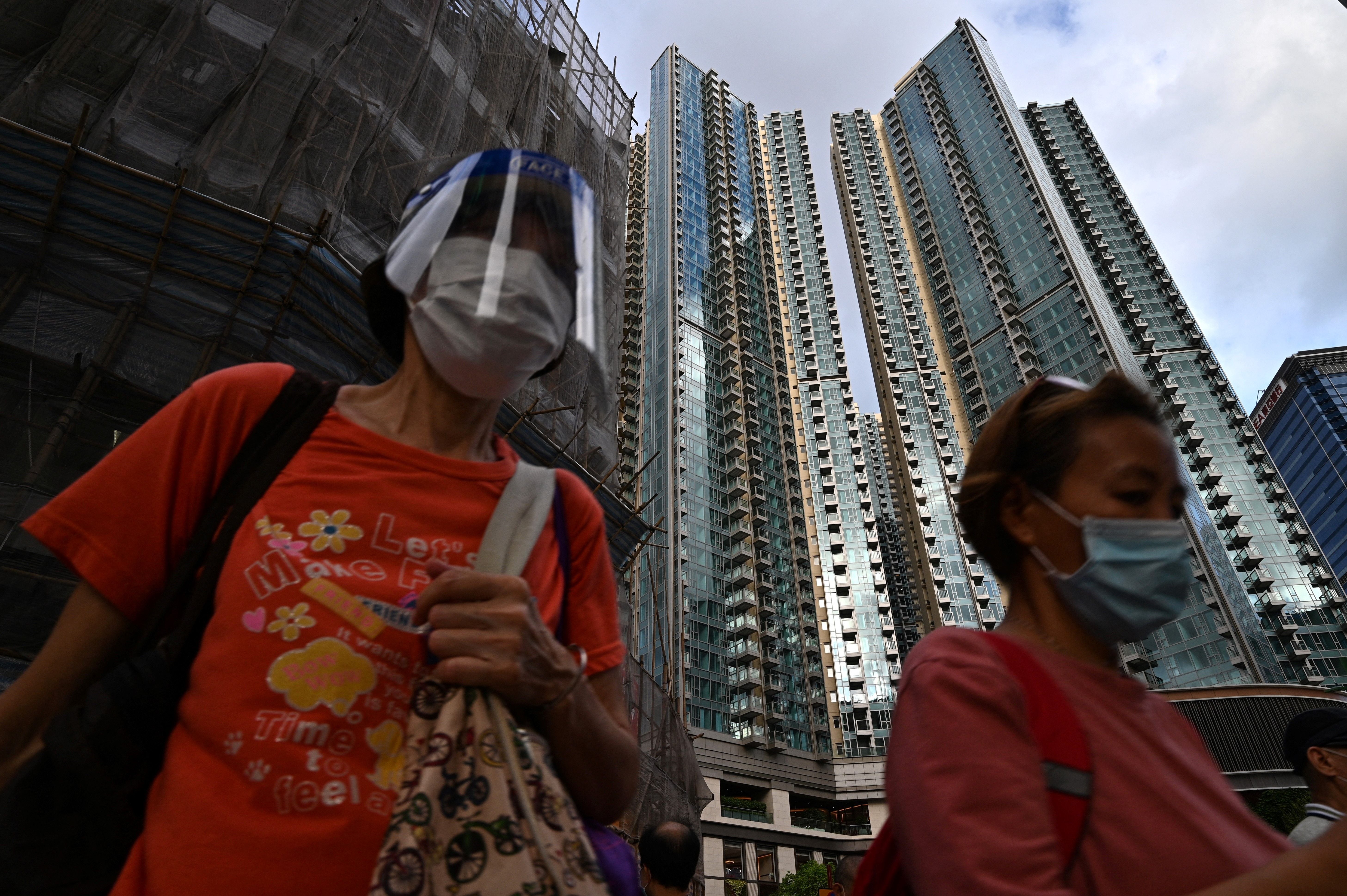Pedestrians wearing masks walk past the Grand Central residential building complex in Hong Kong