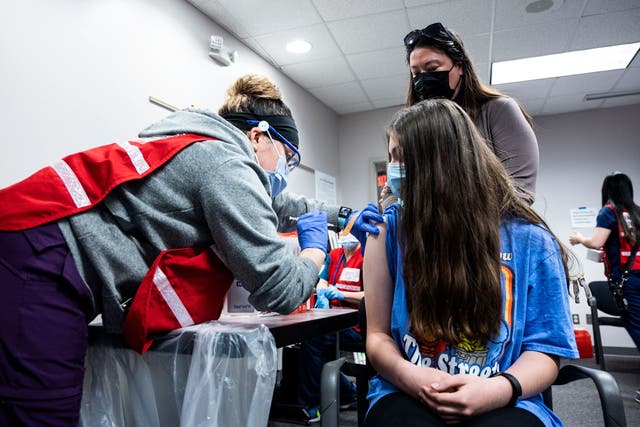 <p>A mother looks on as her daughter gets a Covid-19 vaccination in Virginia on 13 May, 2021. A new poll has found that a quarter of adults in the United States do not intend to get their children vaccinated against Covid-19</p>