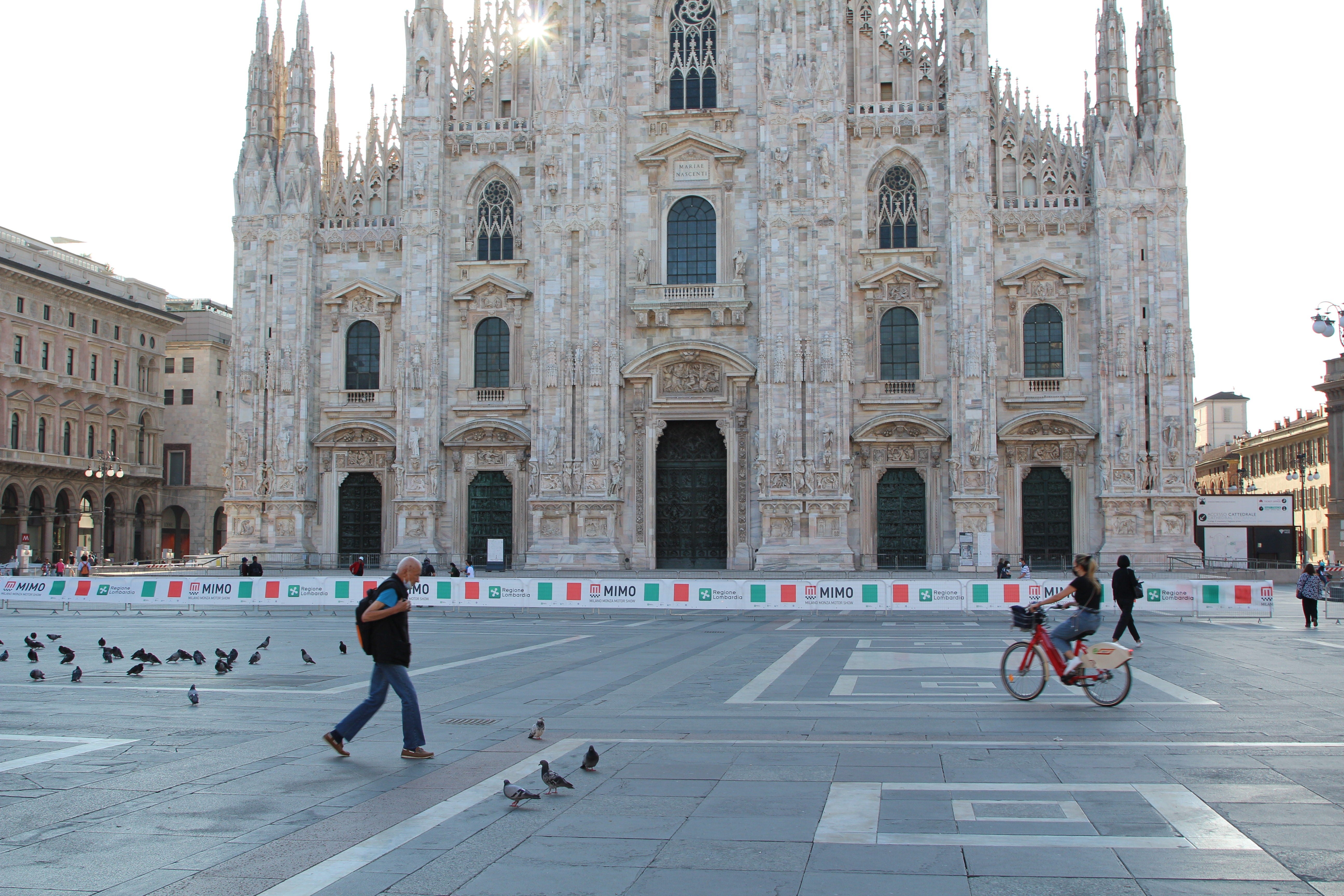 A cyclist and a pedestrian pass Milan’s Duomo