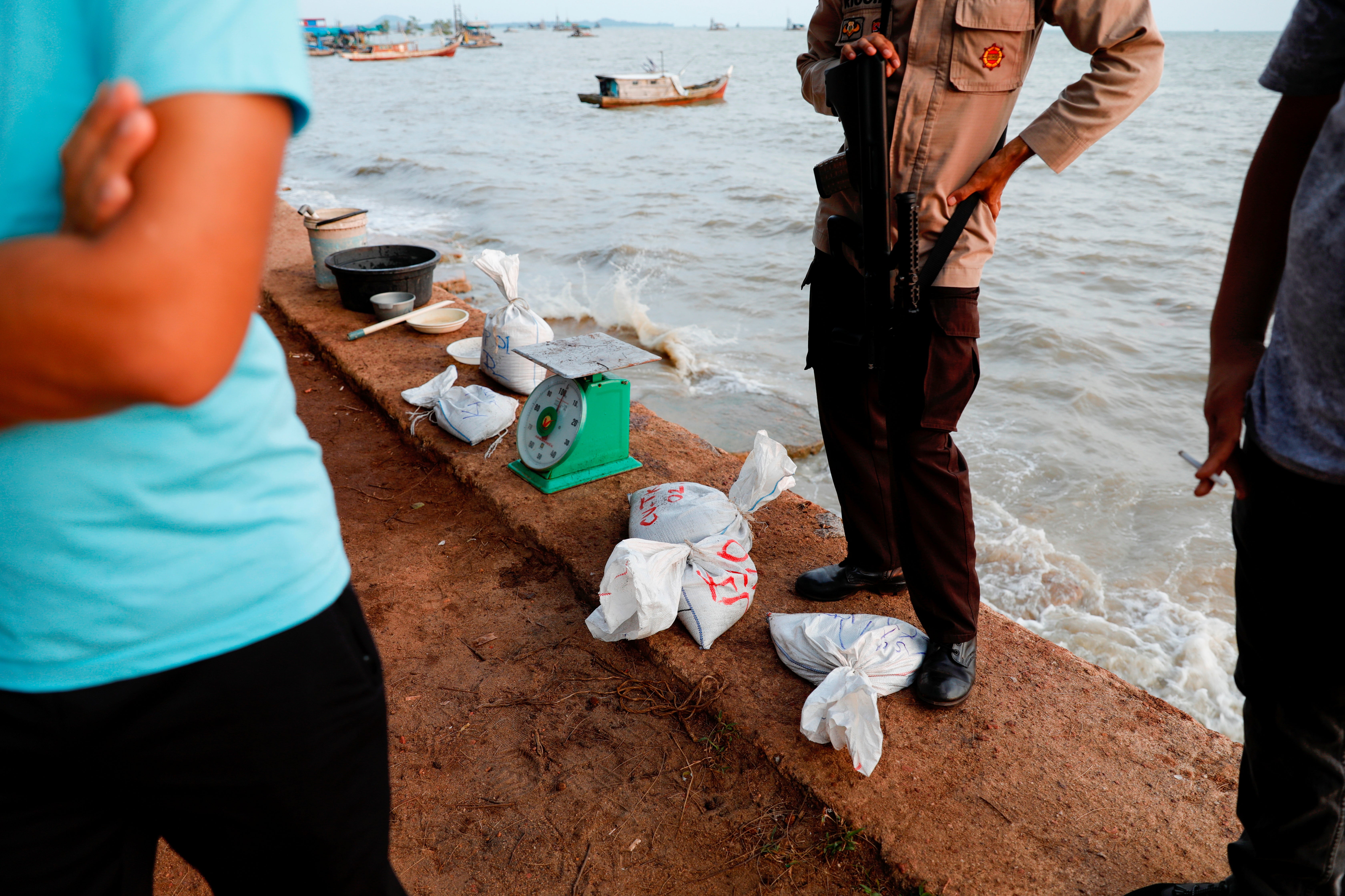 Sacks of tin sand are seen guarded by an armed police officer during the checking and weighing process