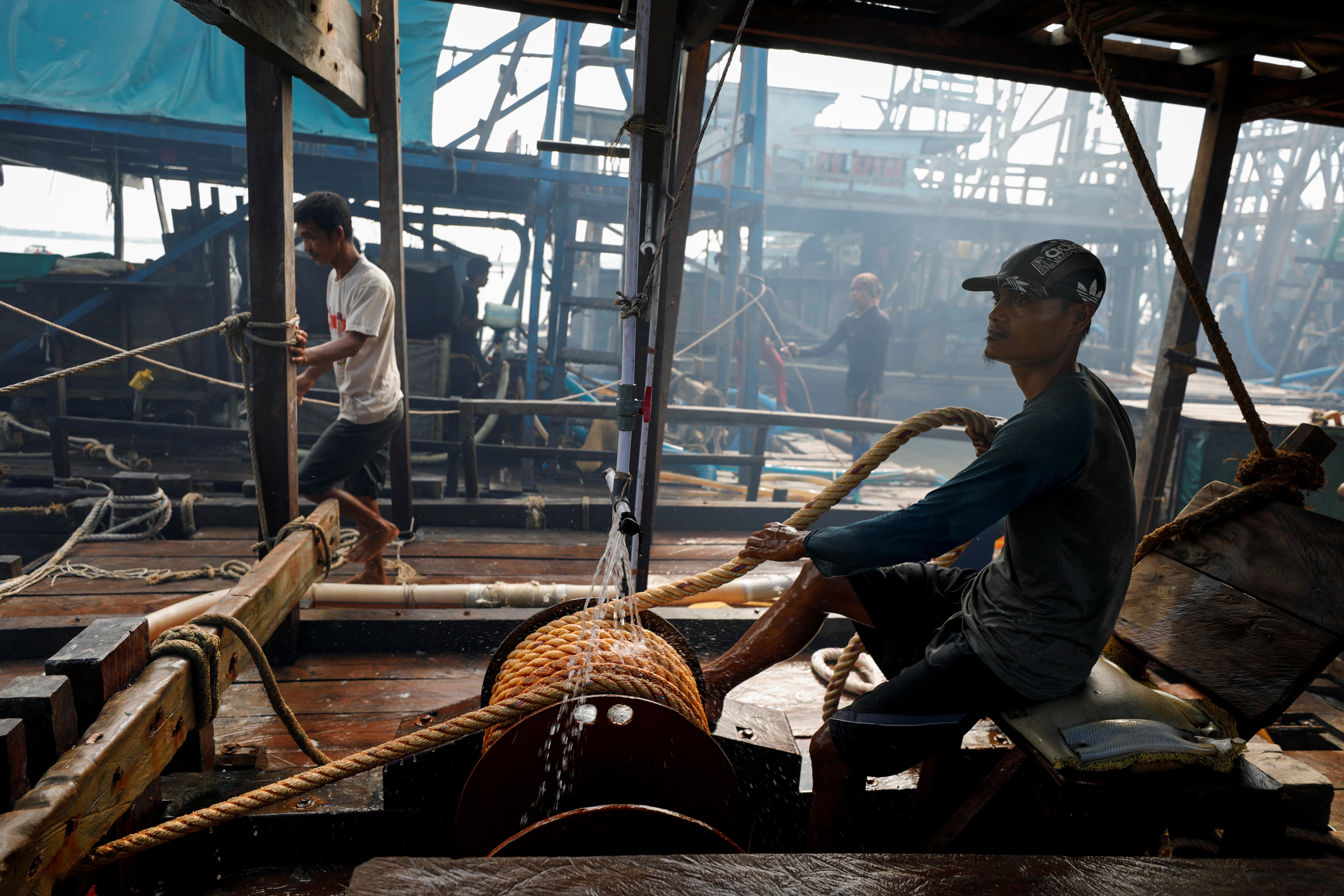 An artisanal tin miner pulls a rope while working on a pontoon