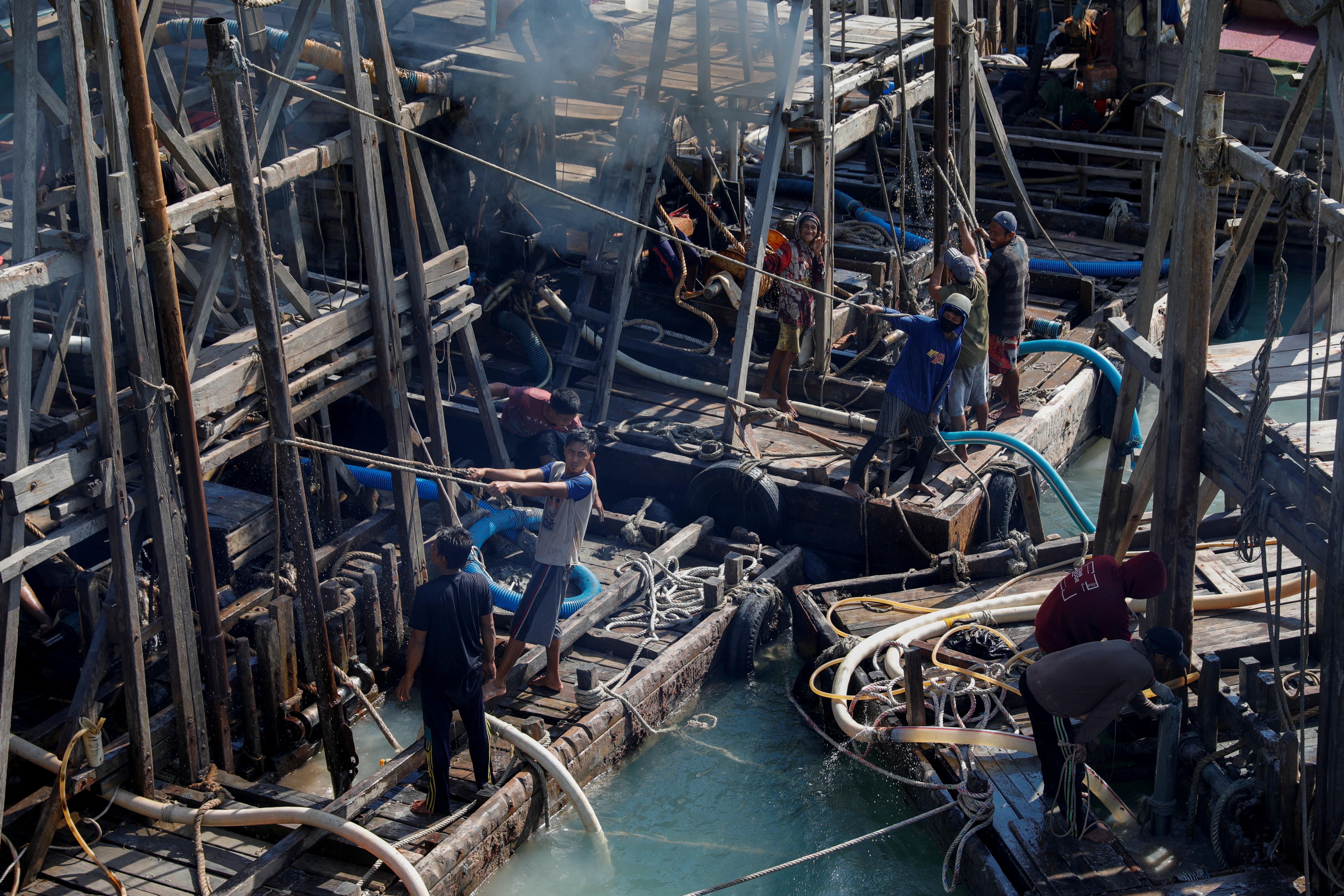 Artisanal tin miners install a suction pipe on a pontoon off the coast of Toboali